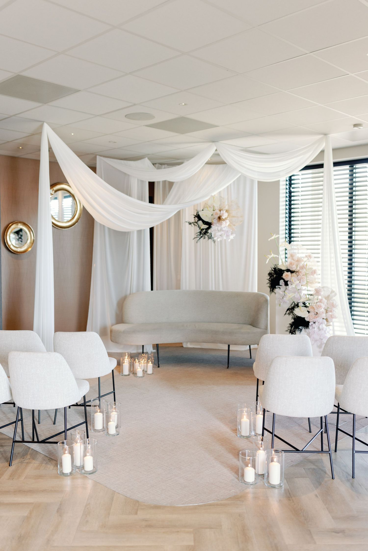 Modern white event space with draped fabric ceiling and elegant seating arrangements.