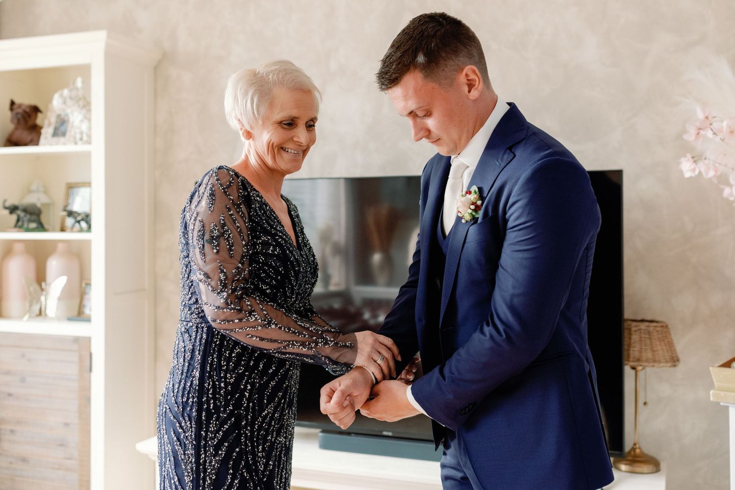 Touching moment between two people during wedding preparations in a bright room.
