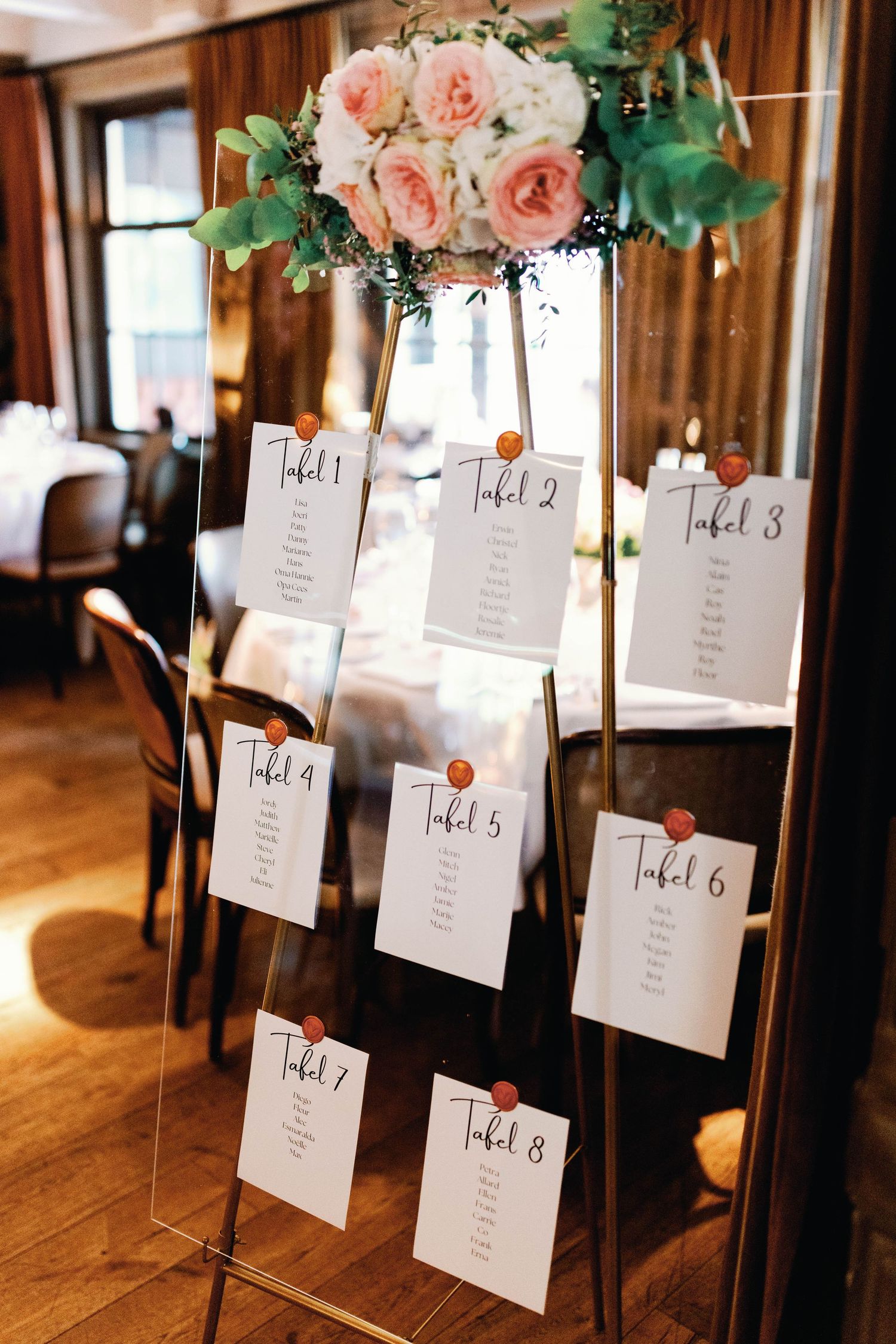 Elegant wedding seating chart displays with blush pink floral arrangements and numbered table cards on mirrored stands.