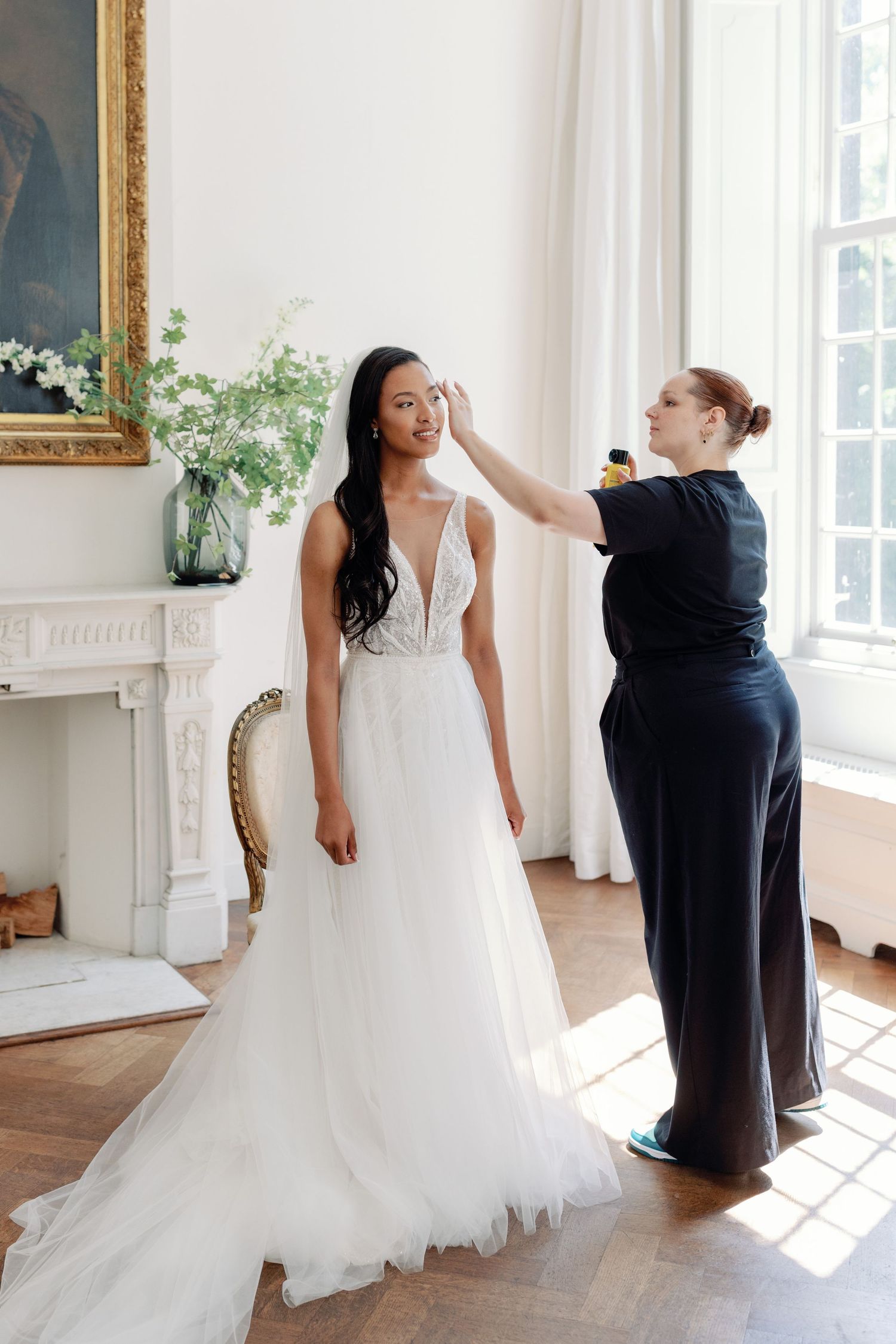A bridal fitting session in a sunlit room with white decor and elegant architectural details.