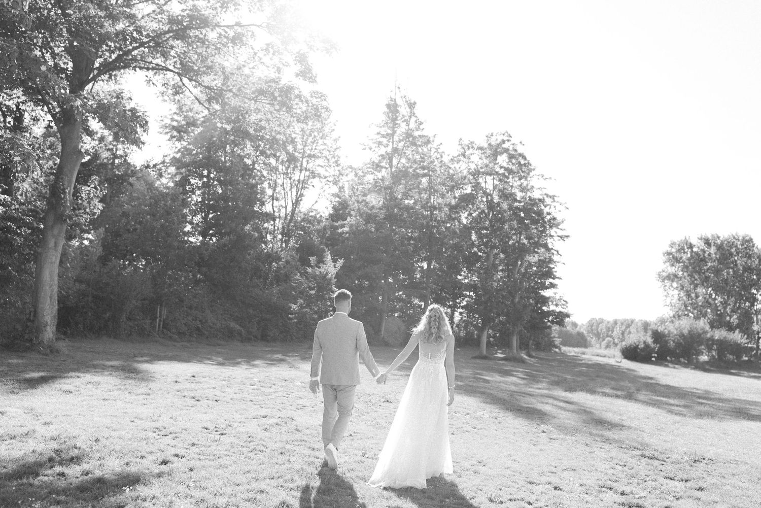 A black and white photo series shows a couple walking through a scenic outdoor setting on their wedding day.