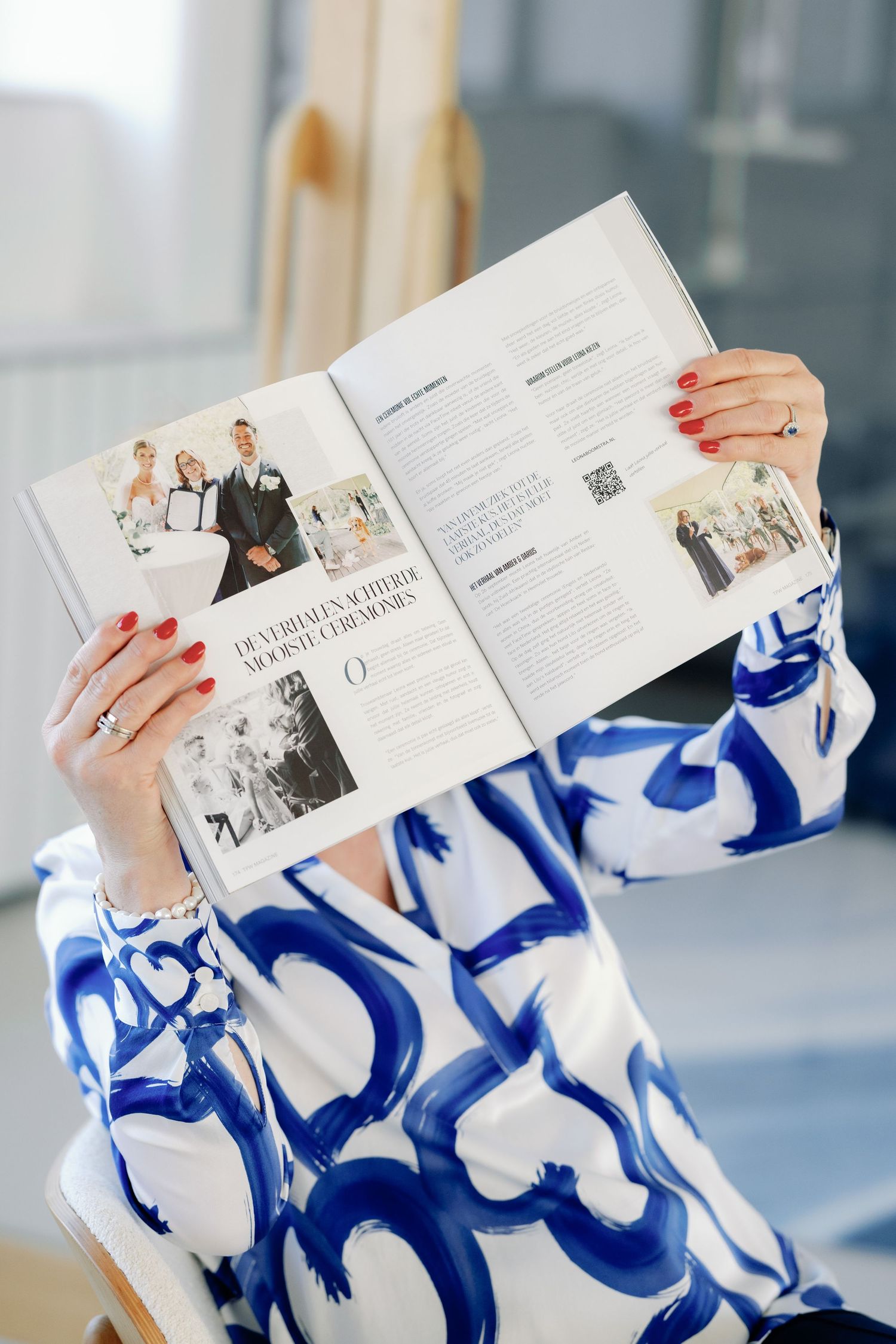 Hands holding open a magazine or brochure with white pages against a blue and white marbled background.
