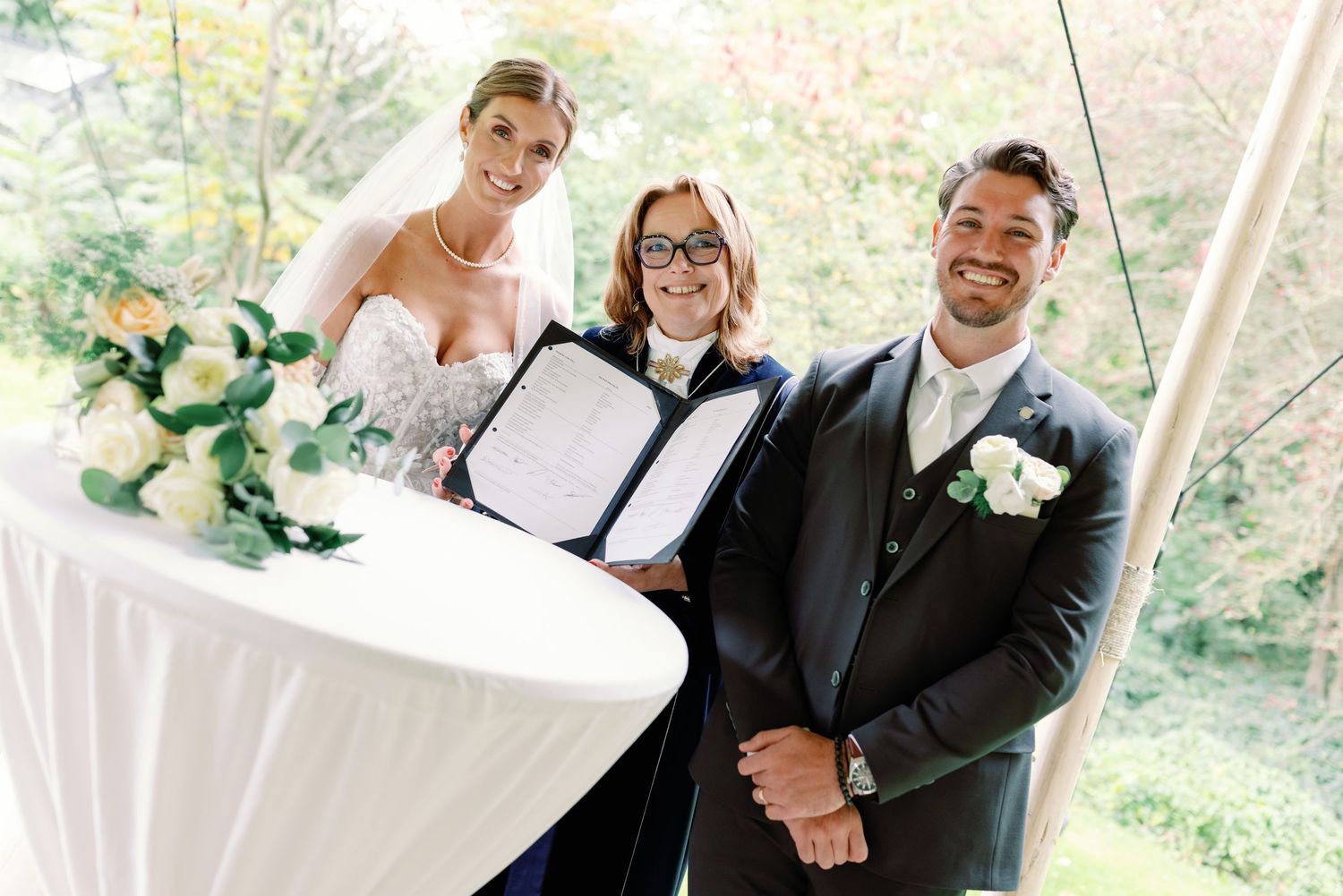 A joyful couple shares a romantic moment during their outdoor wedding celebration in a natural setting.