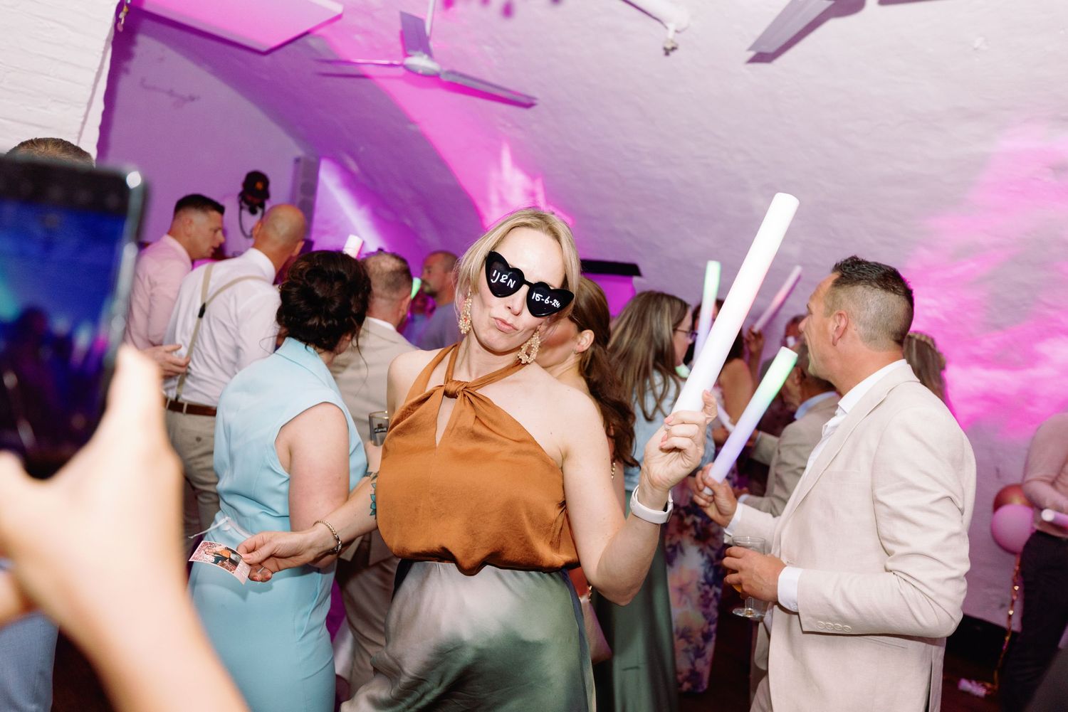 People dancing and socializing at a party with purple lighting and a festive atmosphere.