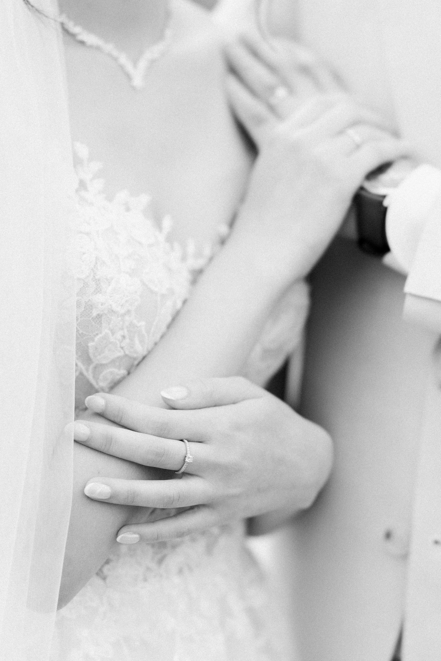 Close-up view of hands adjusting details on an elegant white wedding dress.
