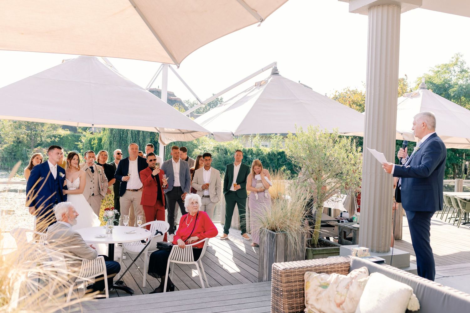White tent canopies set up for an outdoor event with guests mingling in the background.