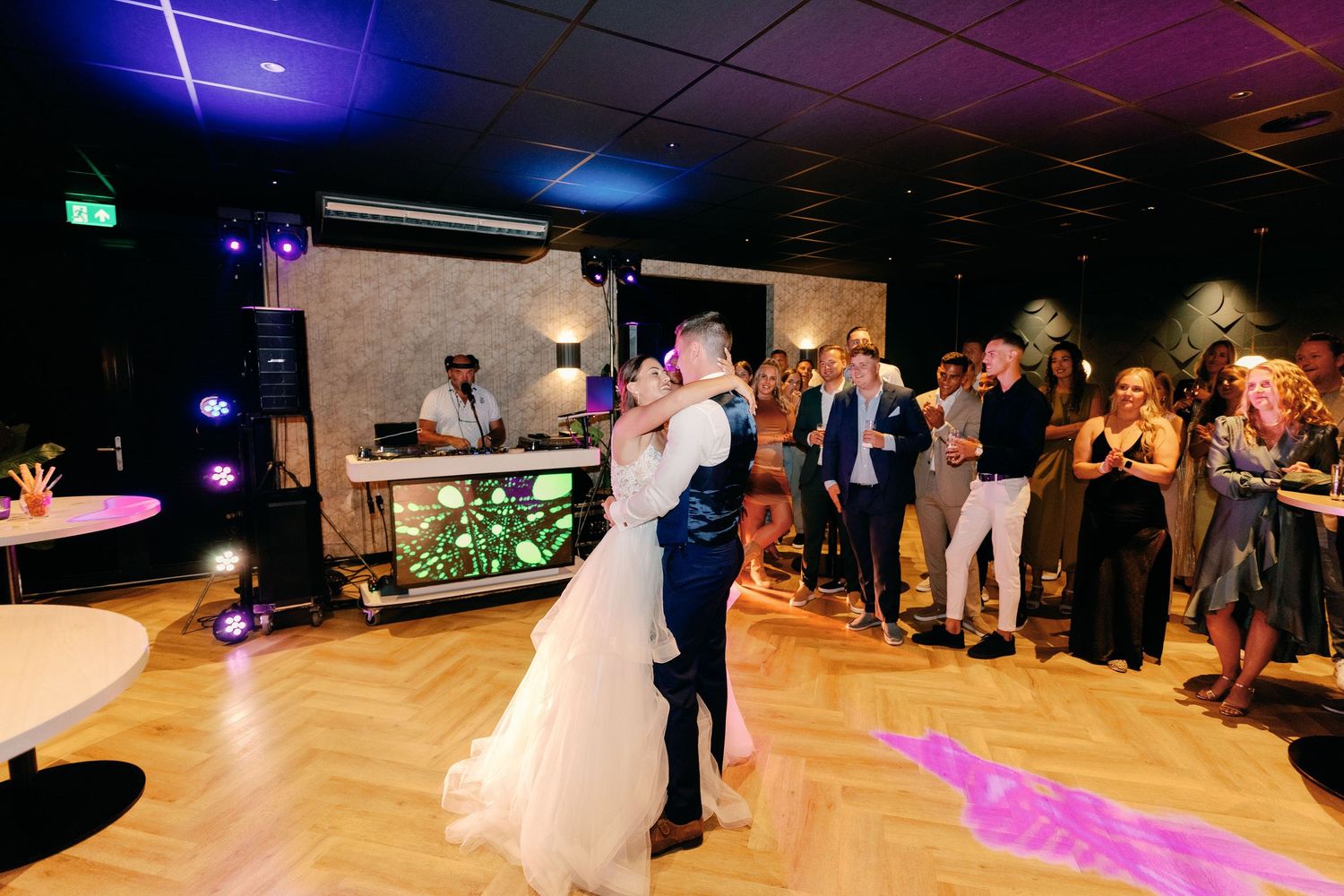 A couple shares an intimate slow dance under blue and purple lighting at their wedding reception.