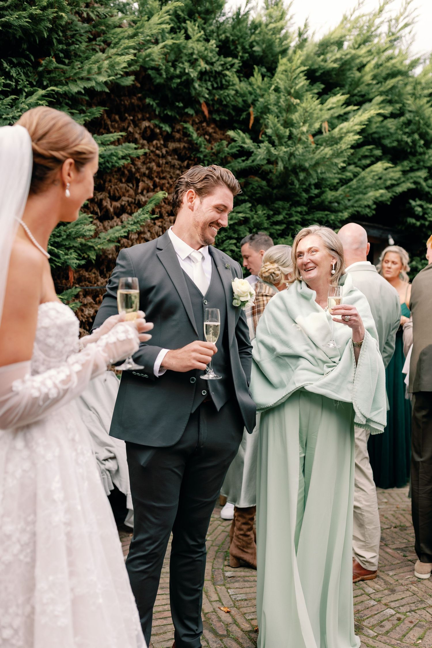 A group in formal attire shares champagne toasts and laughter at an outdoor celebration.