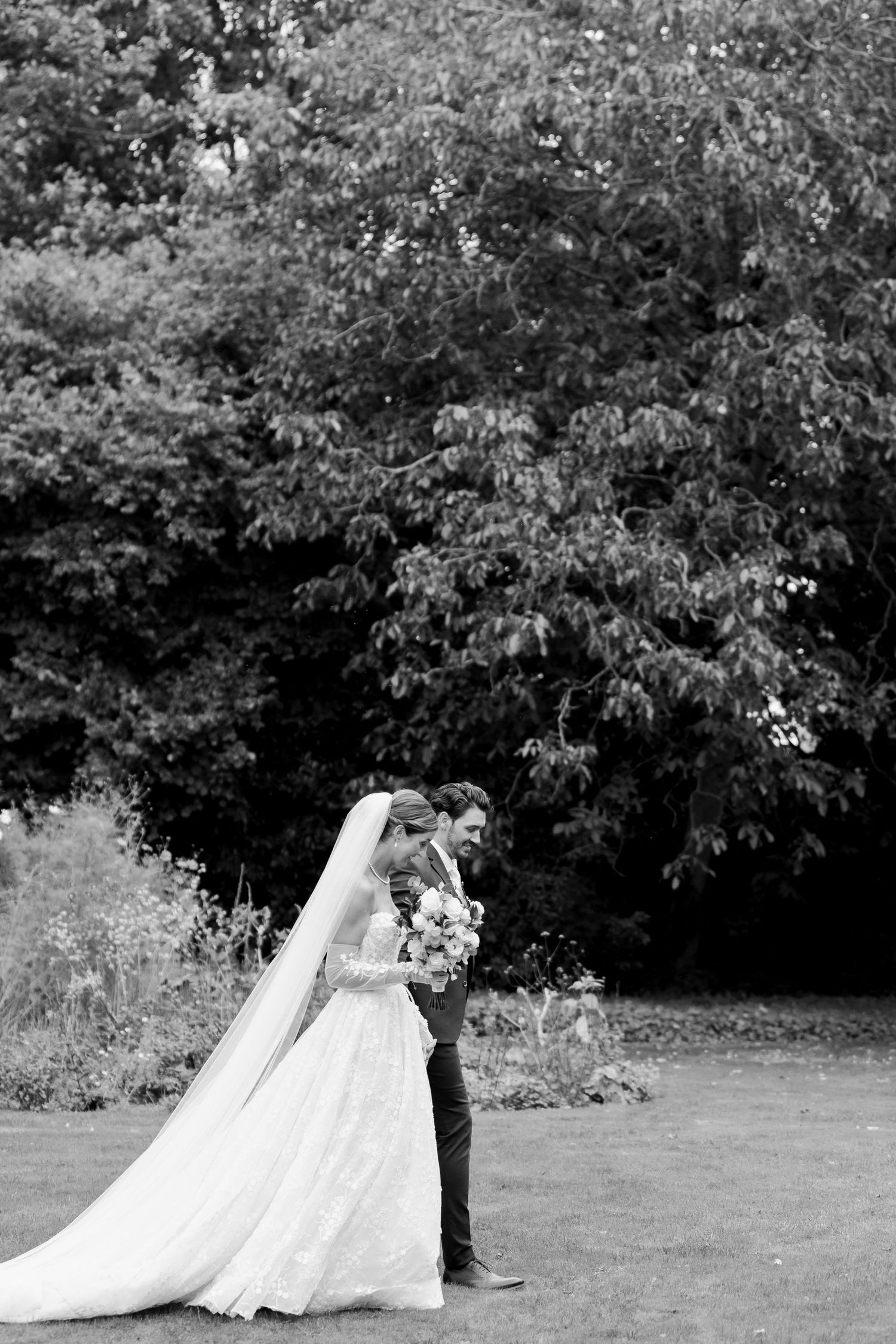 A wedding couple walks together on a grassy lawn with trees in the background, shown in a sequence of five photos.