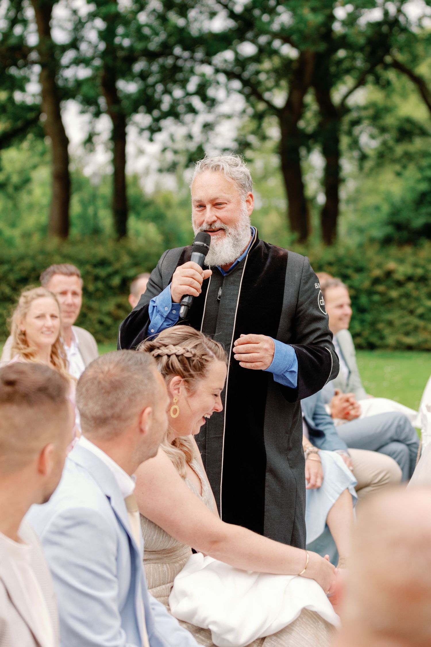 Magician performs entertaining card tricks for a delighted outdoor audience at a summer gathering.