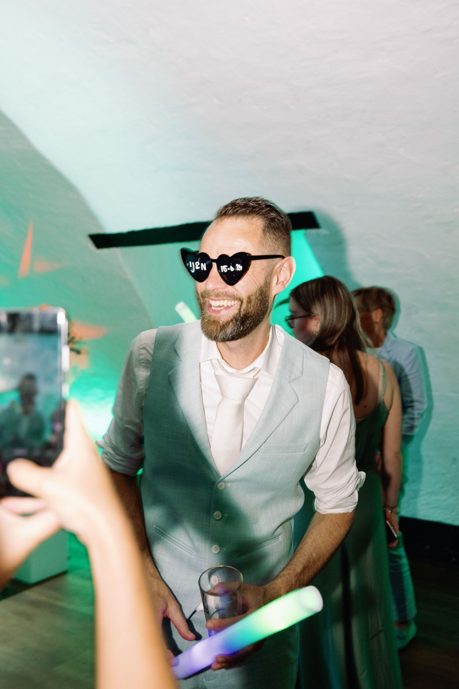 A sequence of party photos showing people dancing and having fun in a dimly lit venue with turquoise lighting.