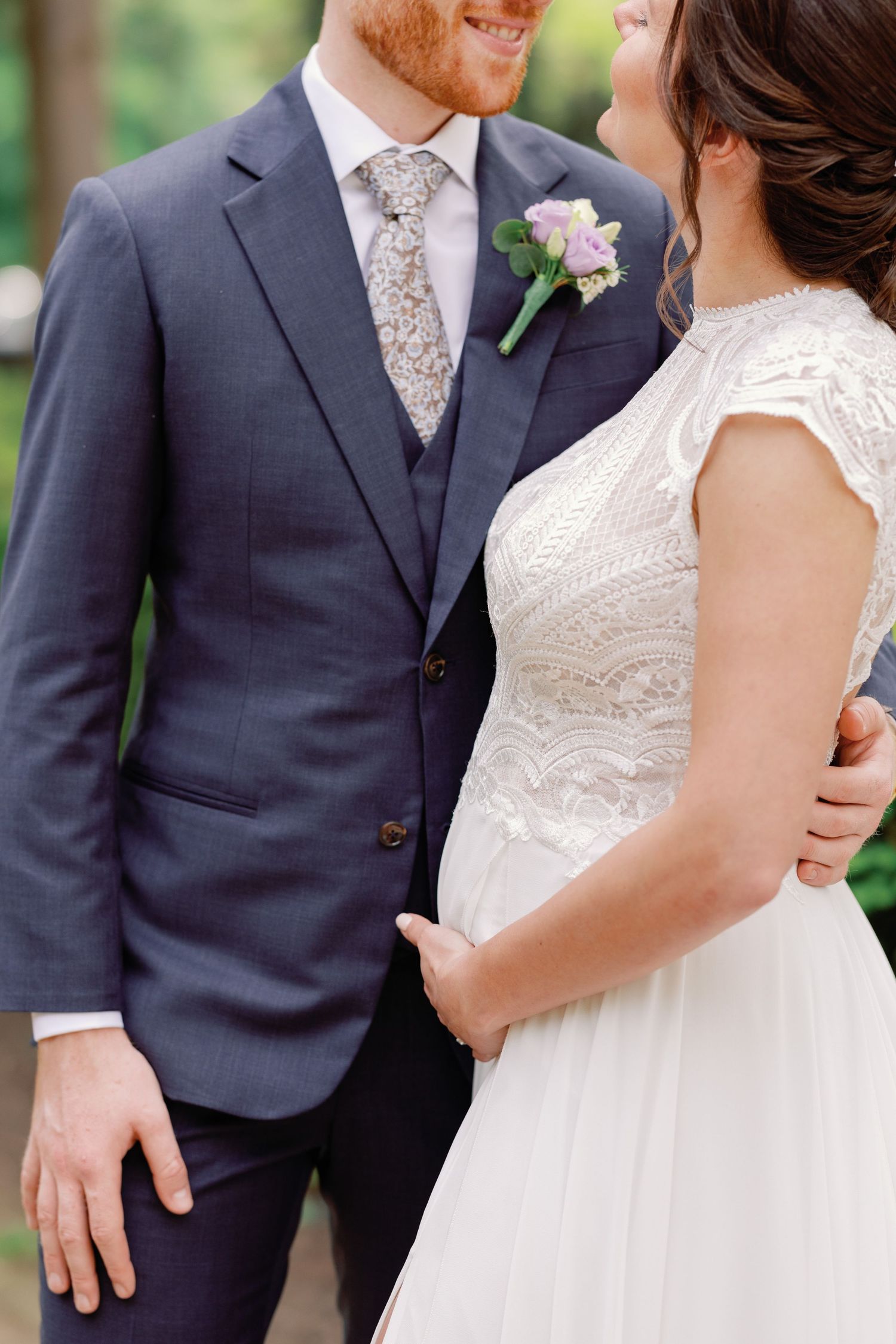 Wedding couple in elegant attire sharing intimate moment outdoors.