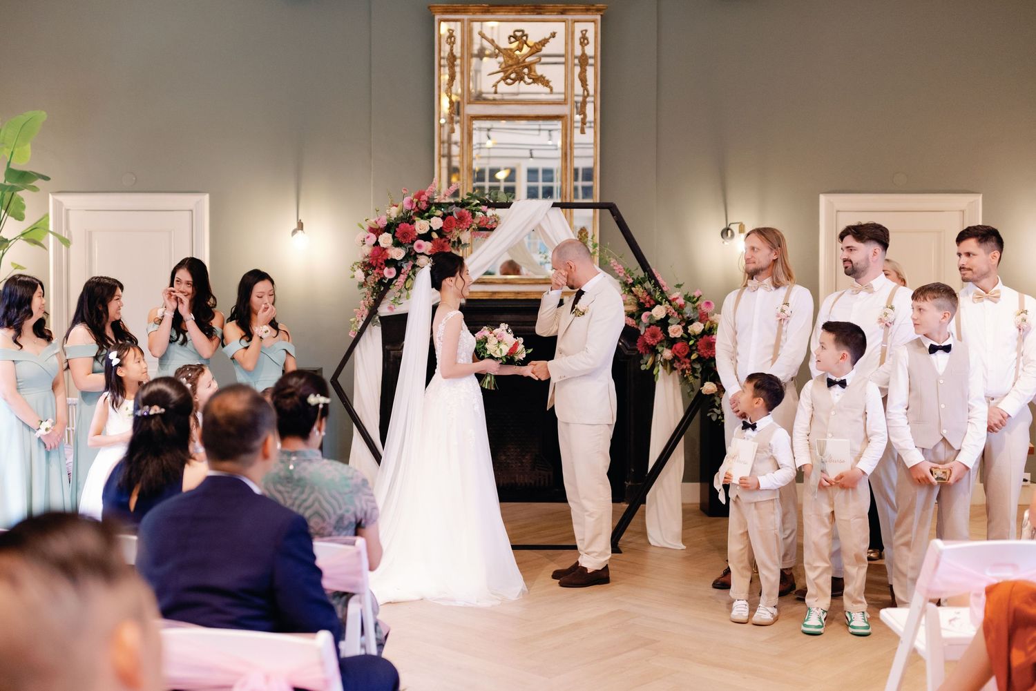 Wedding party dancing and celebrating during reception in elegant venue with stained glass windows and warm lighting.