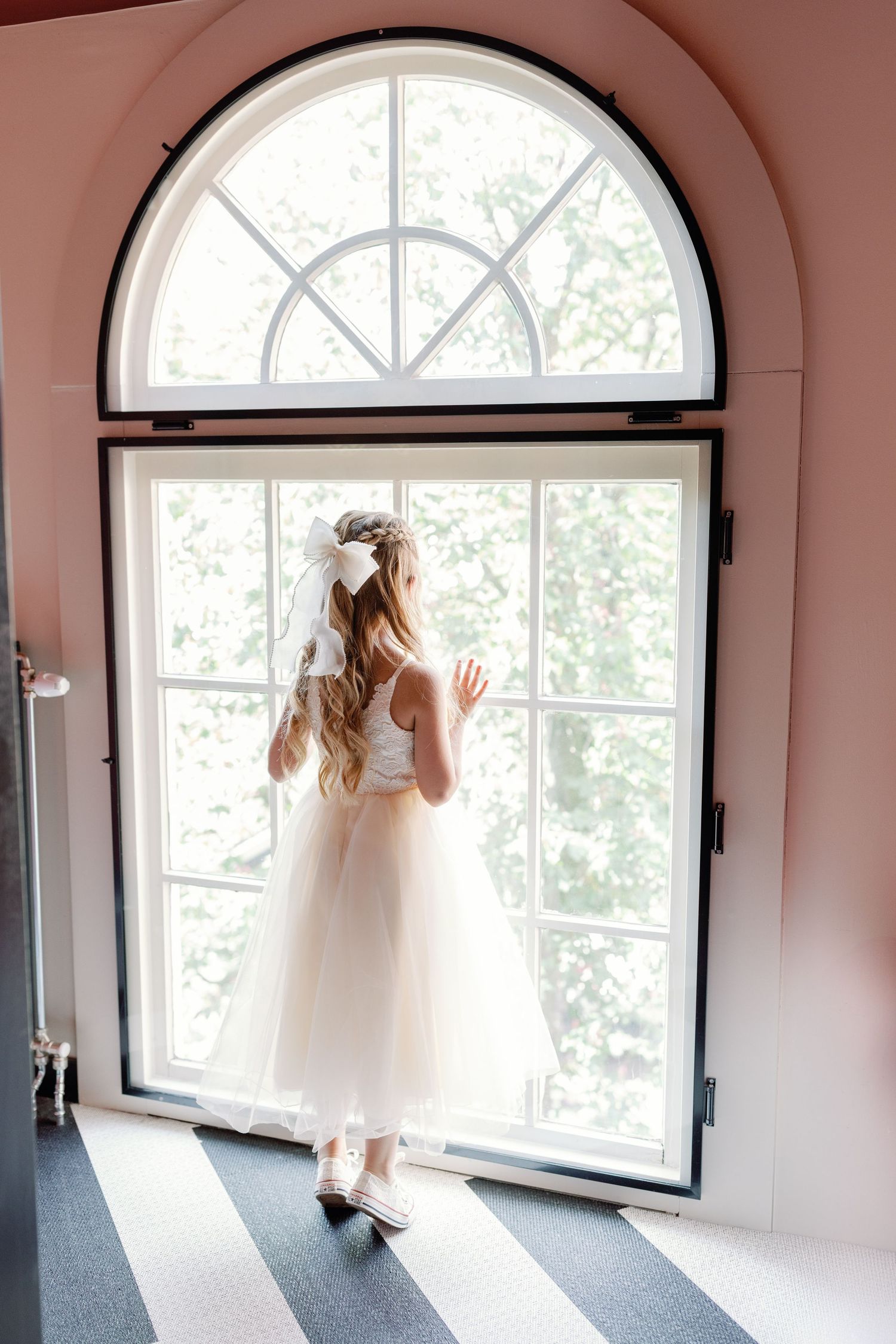 Four sequential photos show a person in a white dress gazing through arched windows in a pink-walled room.