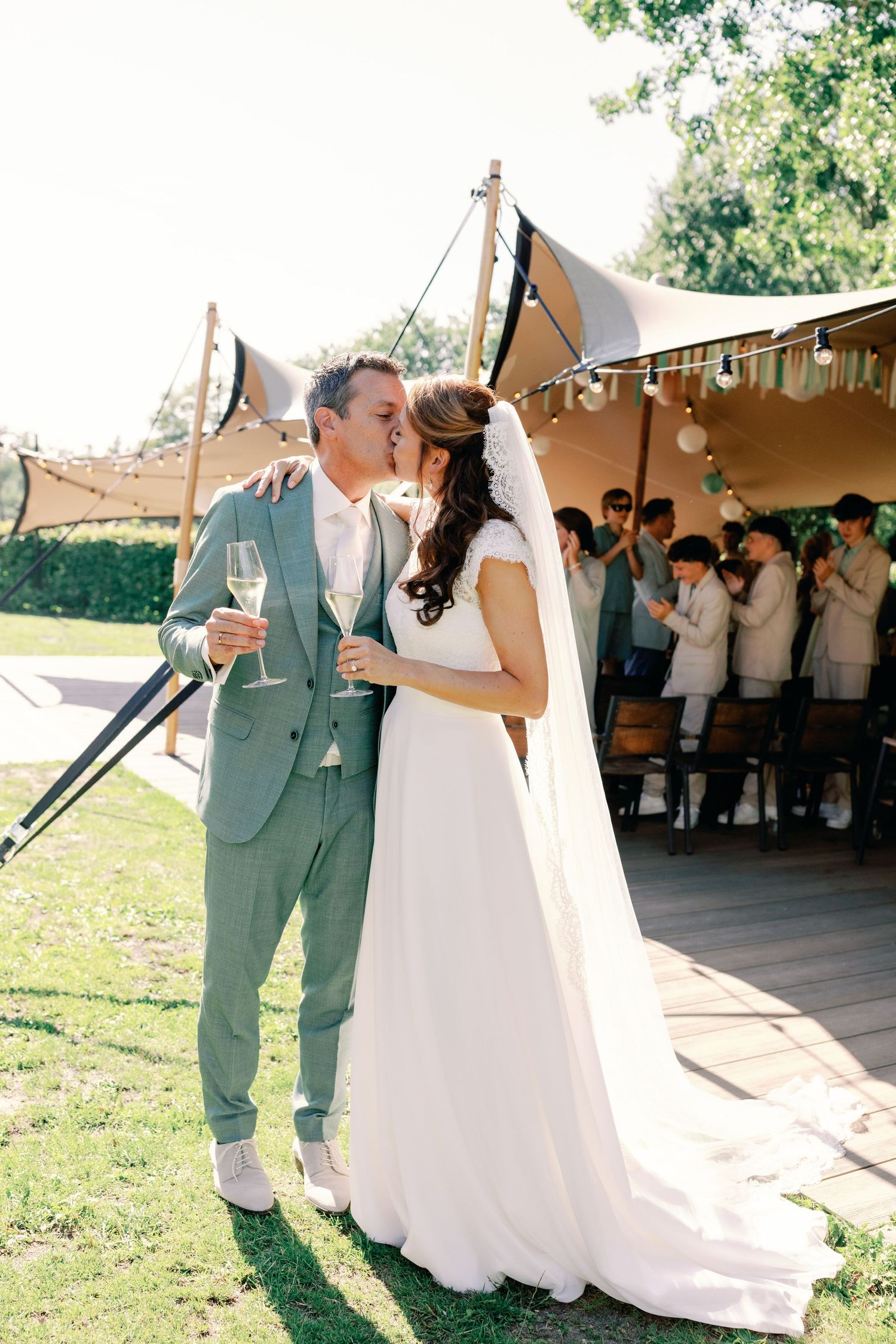A couple shares their first dance at an outdoor wedding reception under a tan tent canopy.