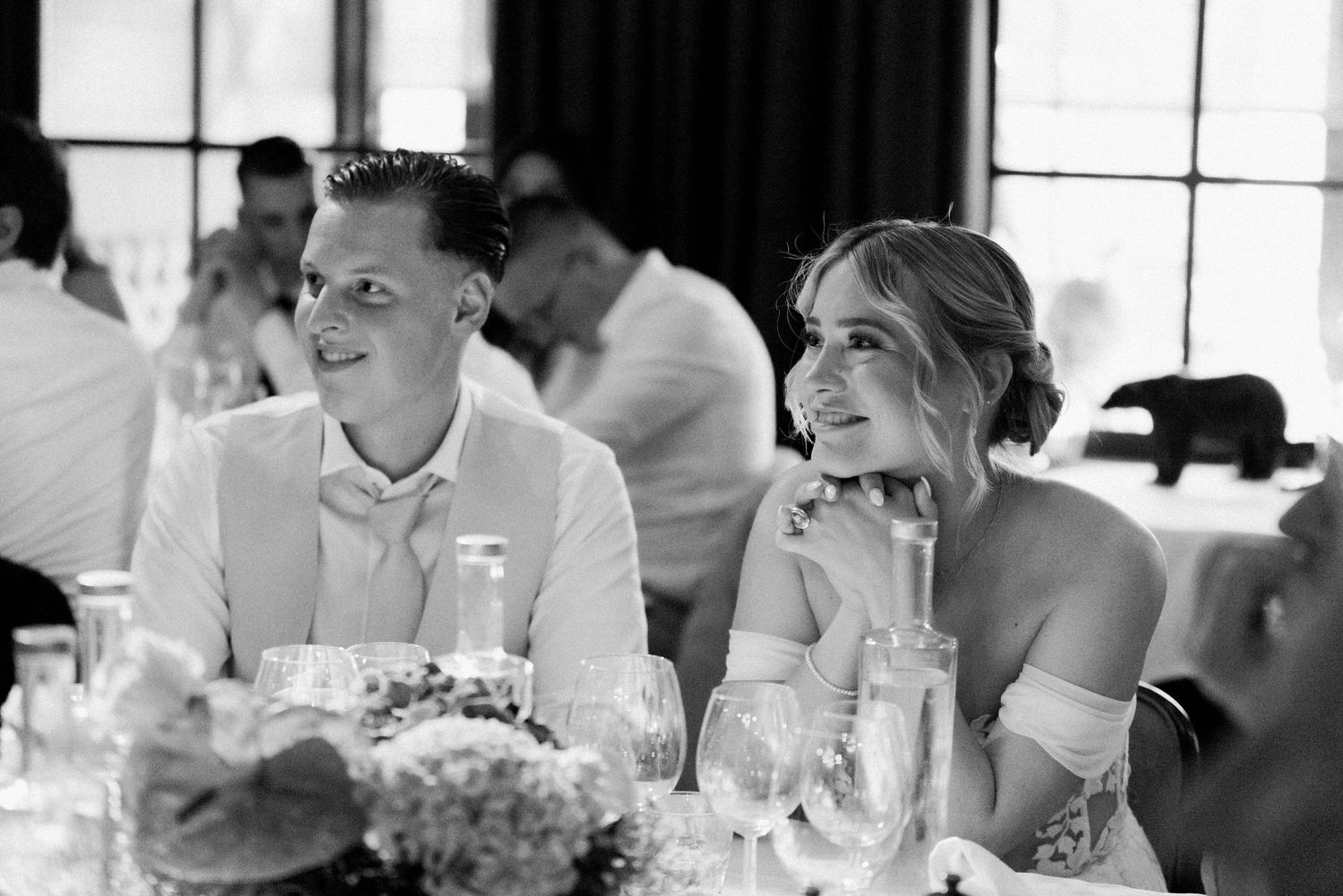 Wedding guests enjoy a candlelit dinner reception at elegantly decorated tables with floral centerpieces.