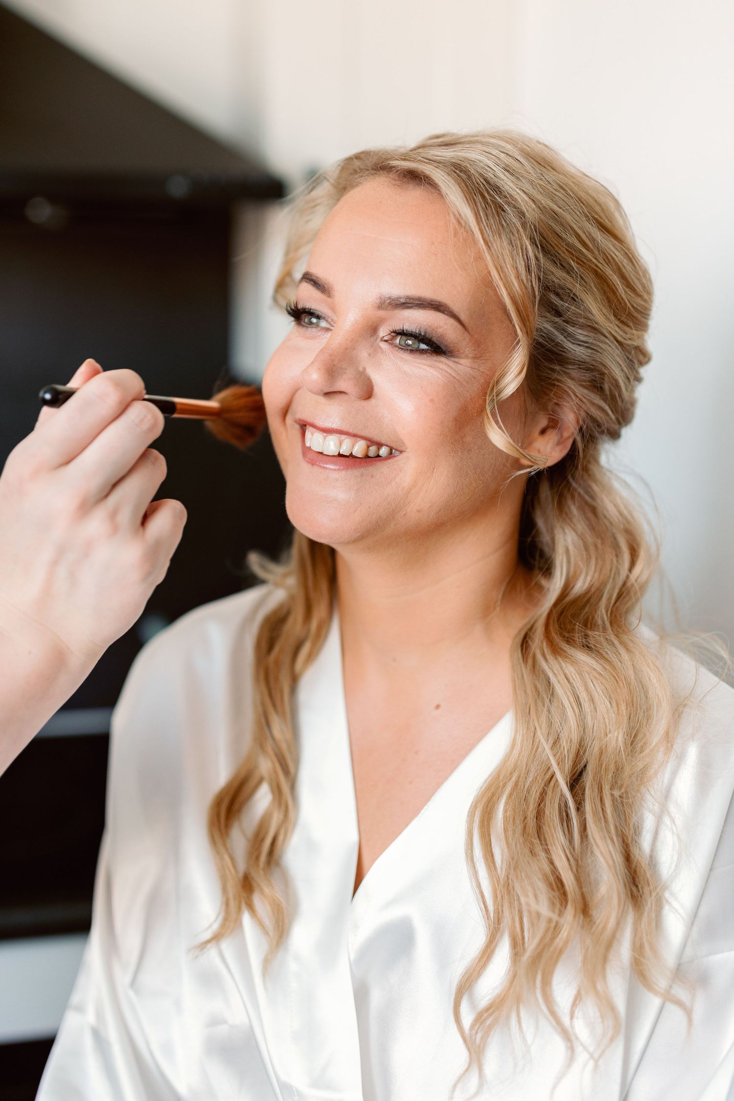 Getting ready on wedding day with makeup application in a white robe.