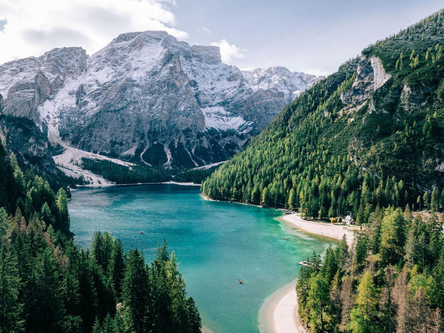 Aerial view of turquoise Lago di Braies lake surrounded by Dolomites mountains and pine forests in South Tyrol, Italy.