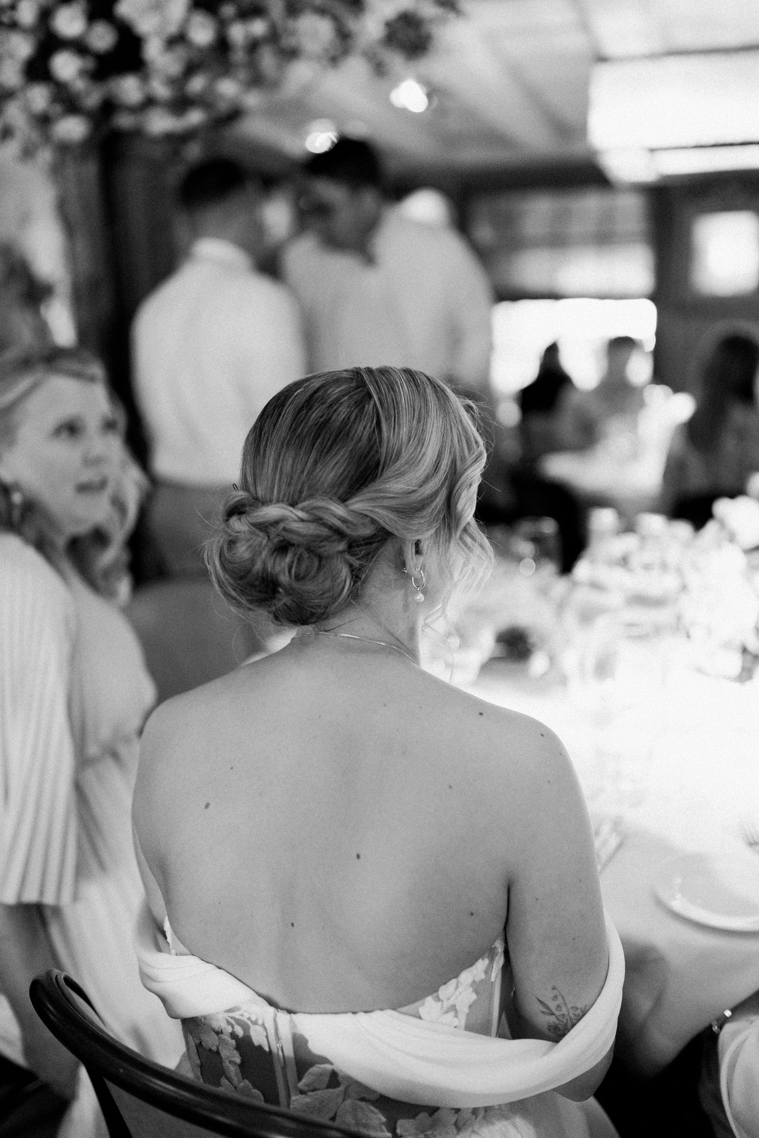 Four black and white photos show a woman in a strapless gown seated at a formal event.