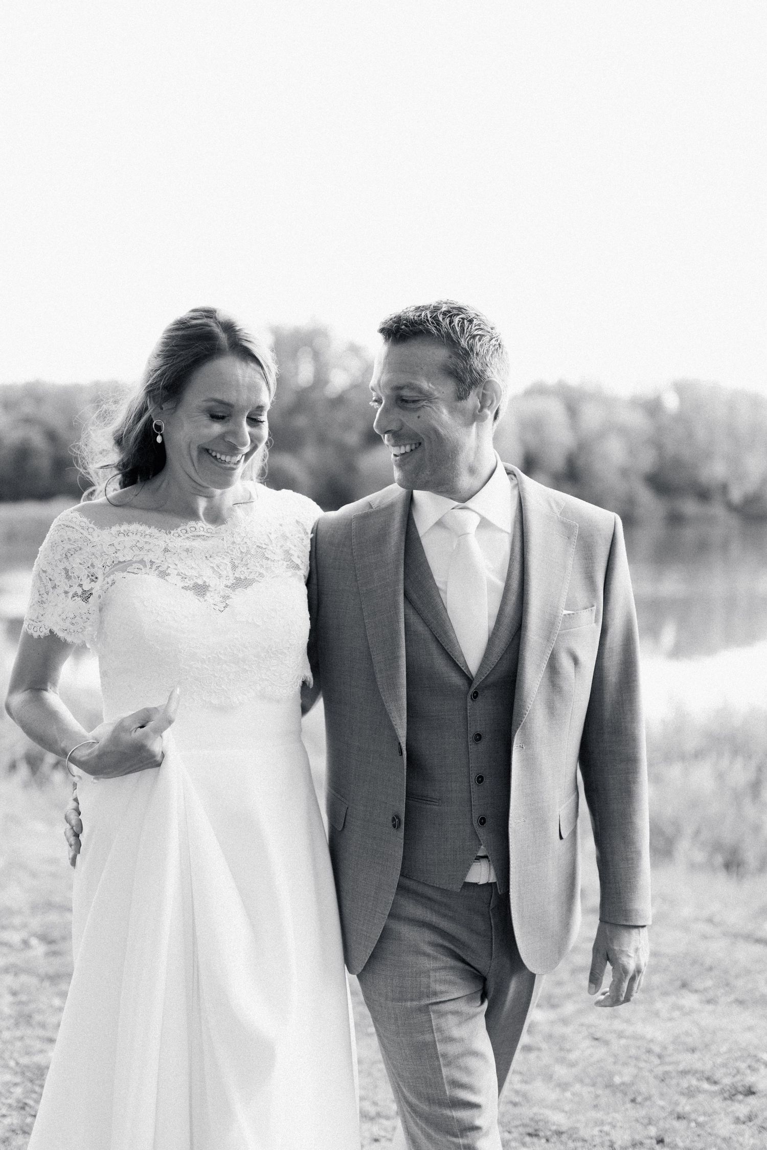A happy couple shares a joyful moment together outdoors on their wedding day in black and white photography.