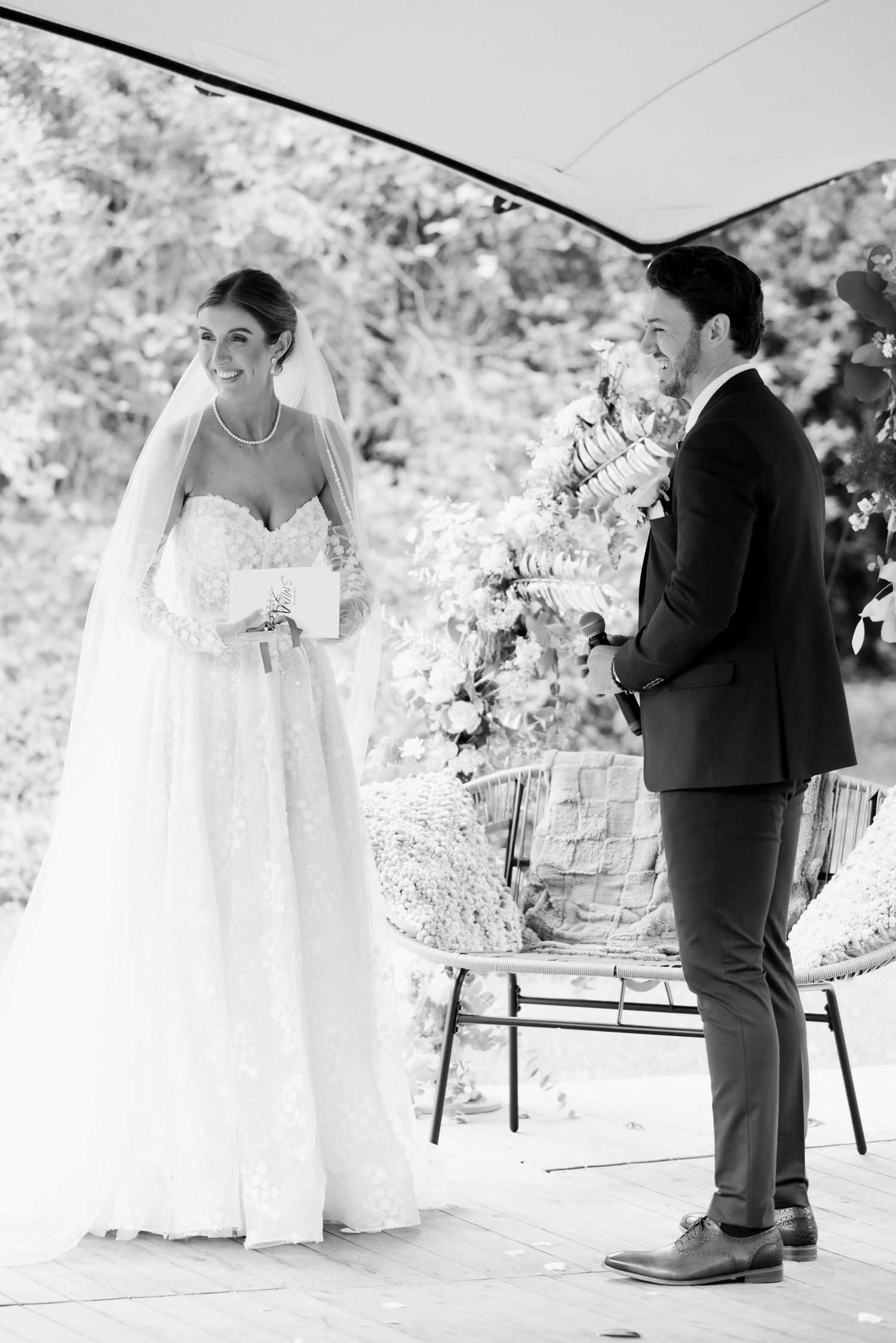 Black and white wedding photo showing a couple at their outdoor ceremony with floral decorations.