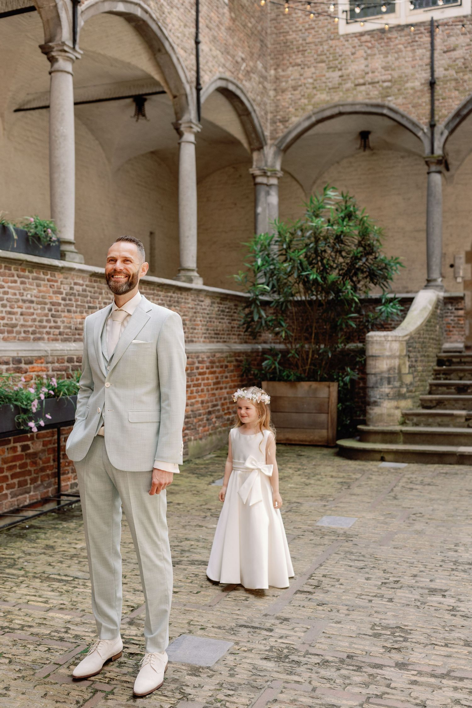A series of wedding photos showing a couple in white attire posing in a historic courtyard with brick walls and columns.