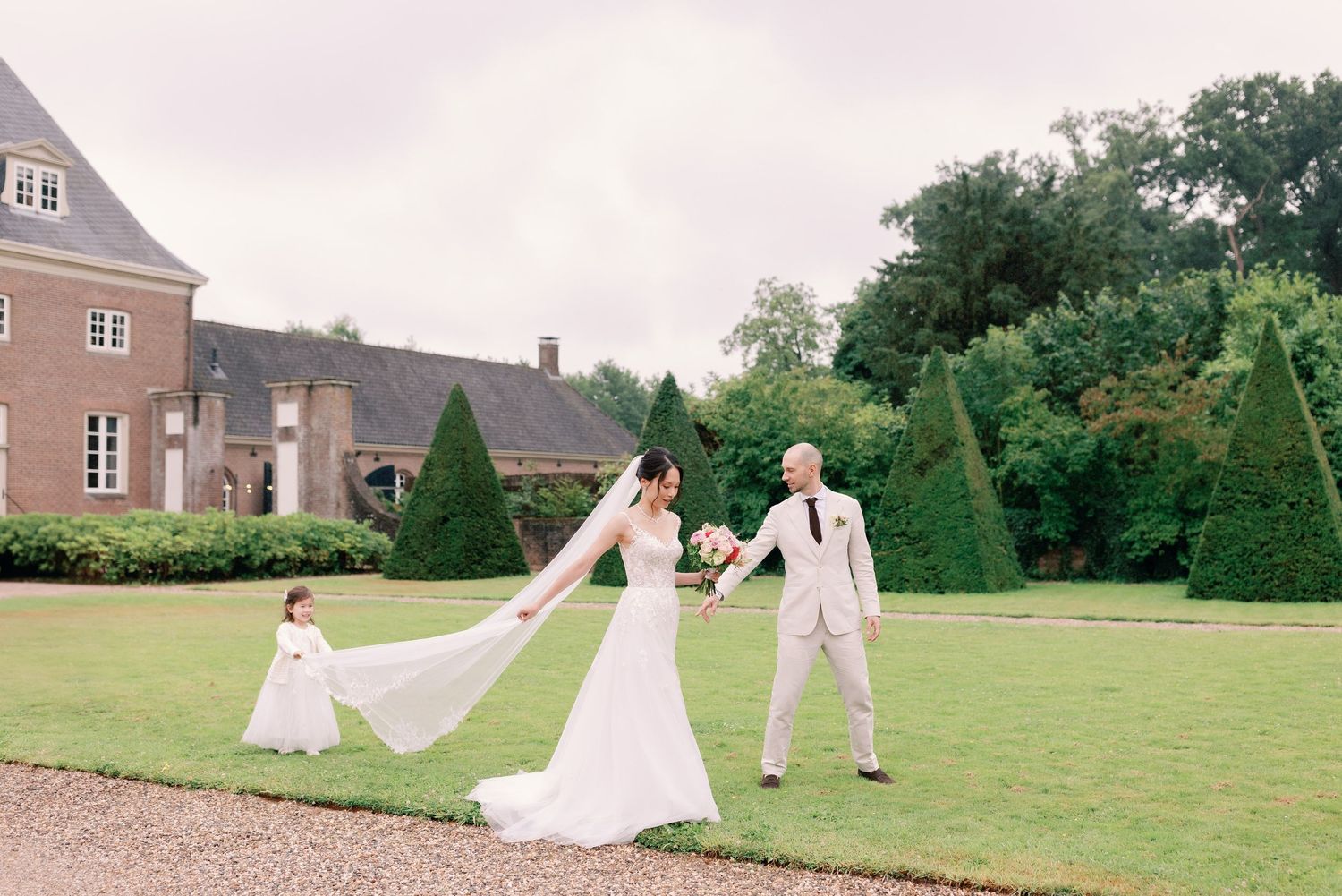 Wedding party having fun on a sprawling lawn in front of a rustic farmhouse.