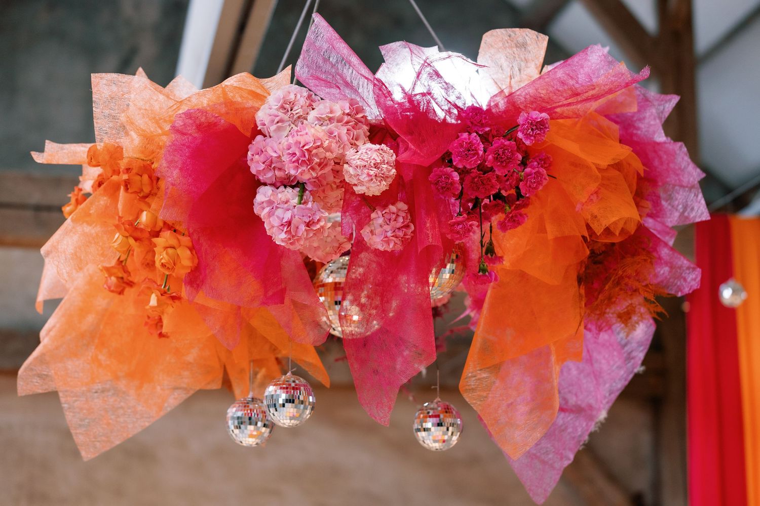 Decorative pink and orange tulle fabric garland with hanging crystal ornaments adorns a festive party space.