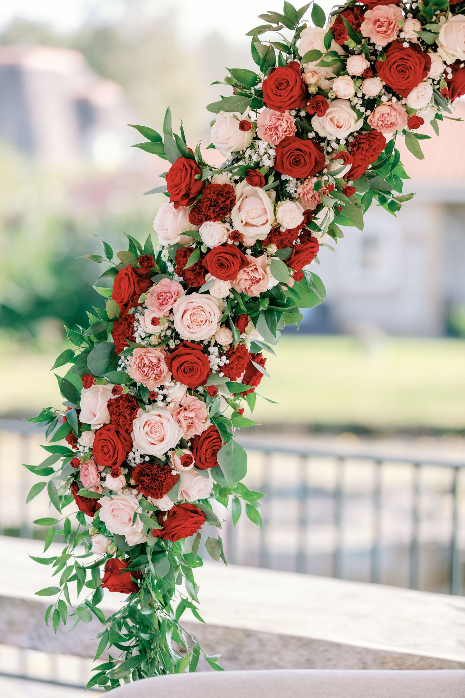 A stunning floral arrangement with red and pink roses cascading with greenery.