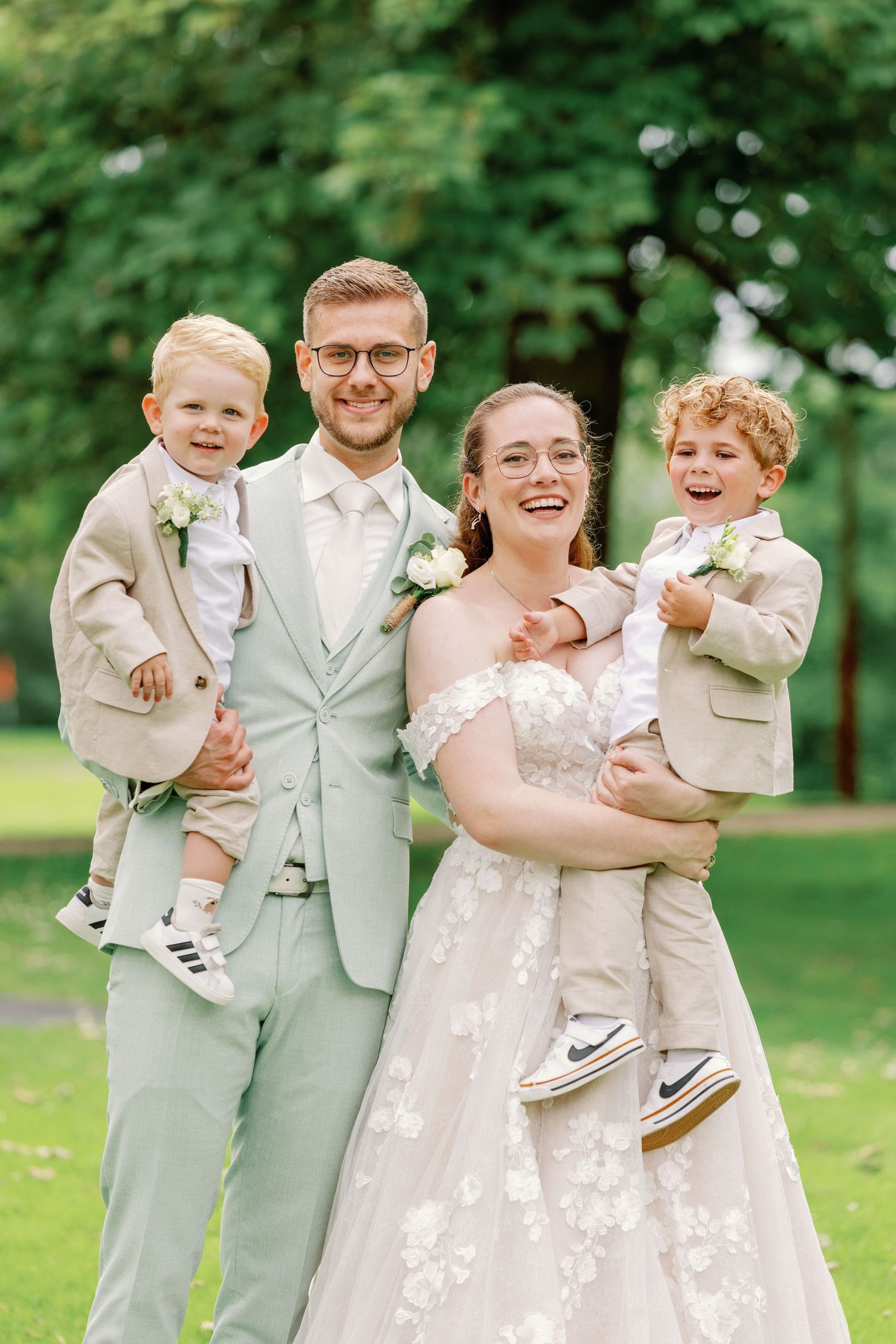 Wedding party wearing coordinated mint green and white attire posing on green lawn.