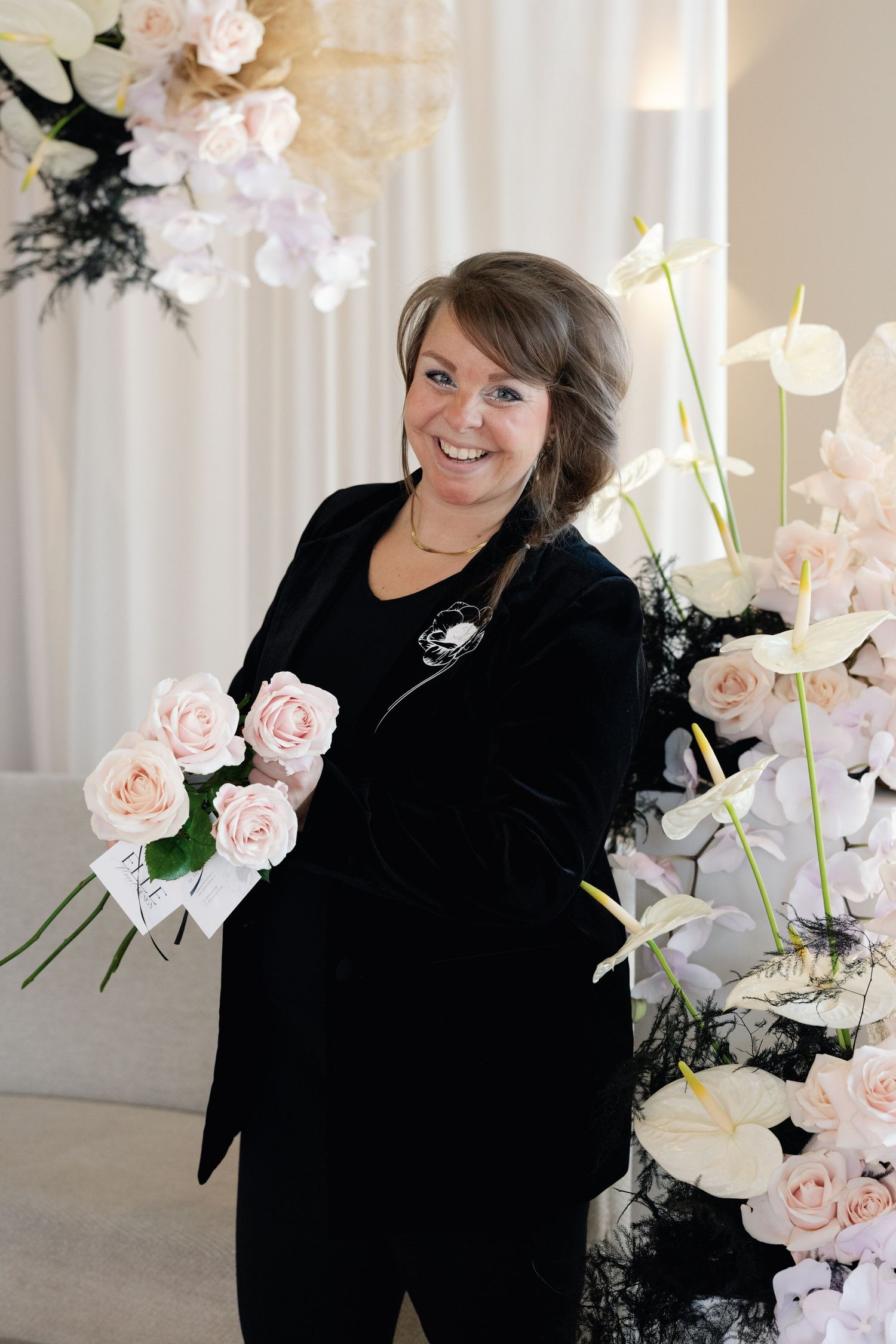 Elegant event space decorated with soft pink roses and white curtains.