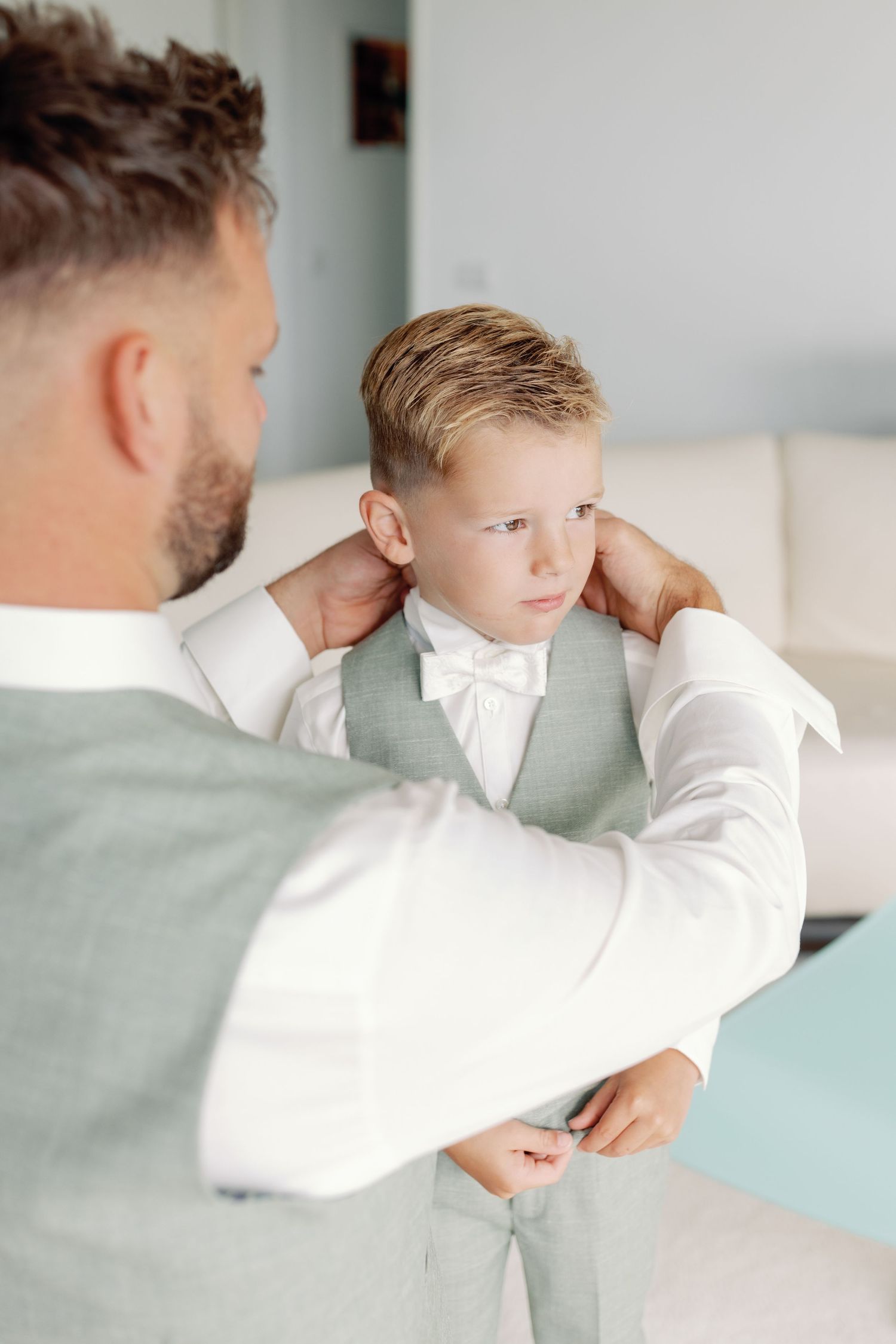 A tender moment between parent and child wearing white shirts as they embrace in a bright, minimalist setting.