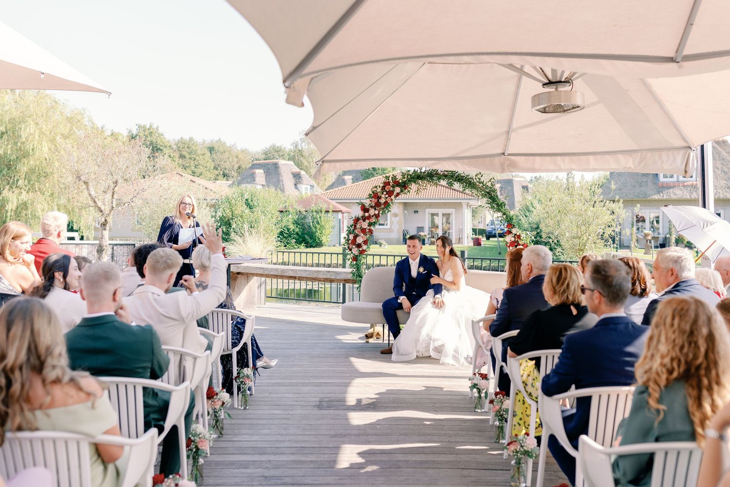 An outdoor wedding ceremony setup with white chairs and a floral arch overlooking a scenic backdrop.