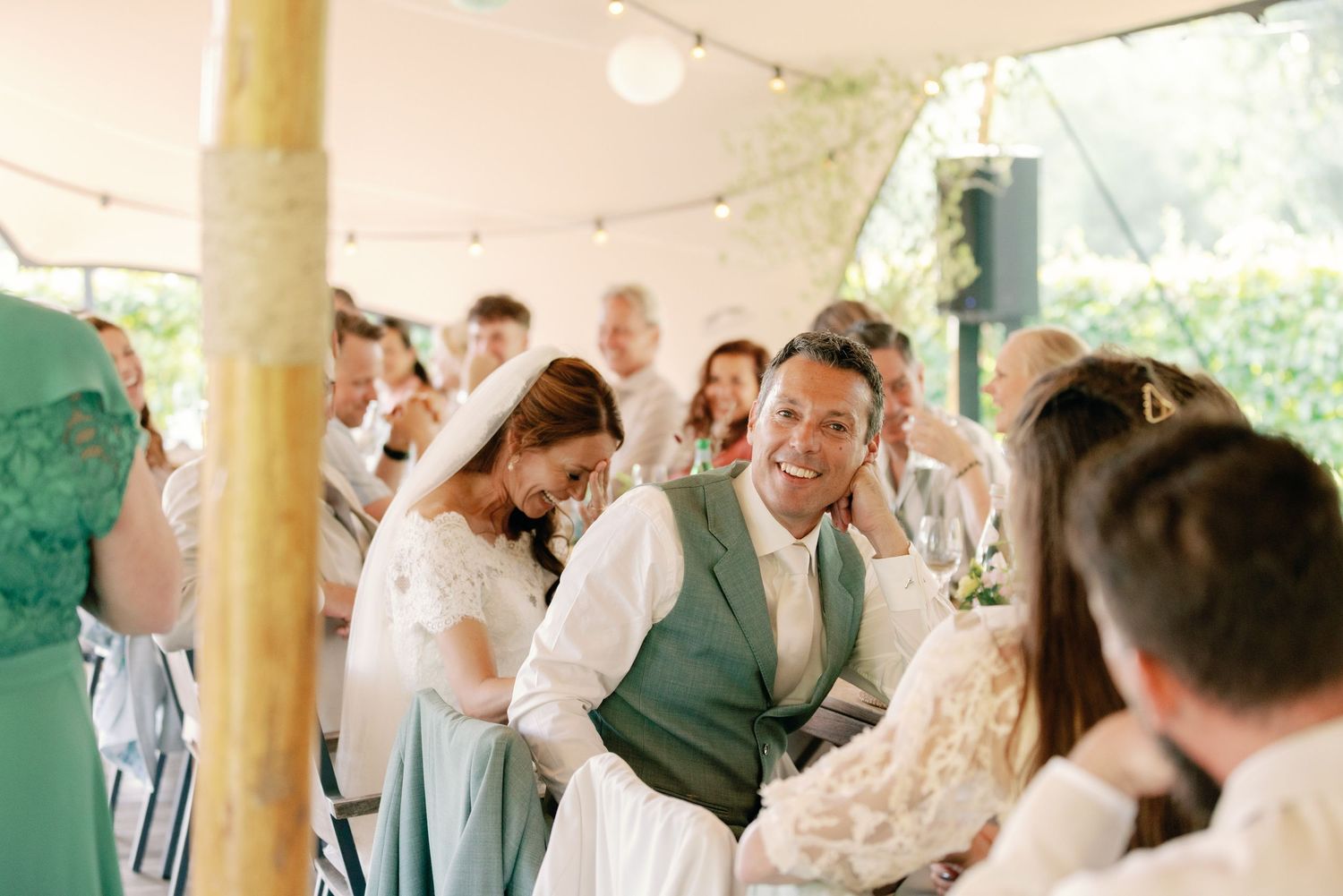 Wedding guests dance and celebrate together under a white tent during an outdoor reception celebration.