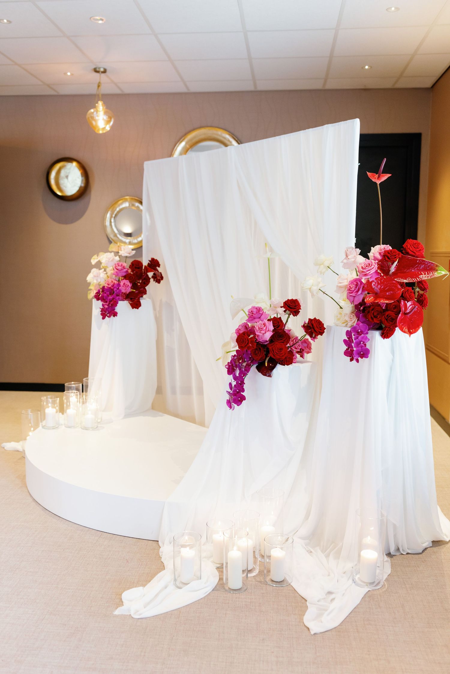 White fabric draping with magenta orchids creates an elegant backdrop display for a special event setup.