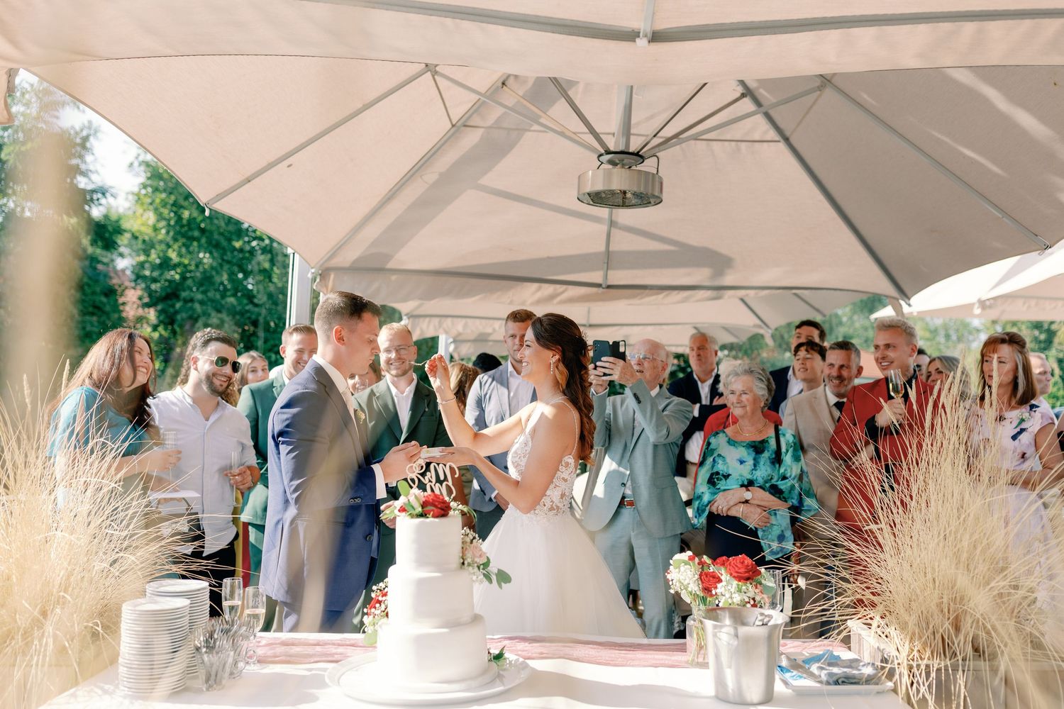 White tent decorated for outdoor wedding reception with natural light filtering through.