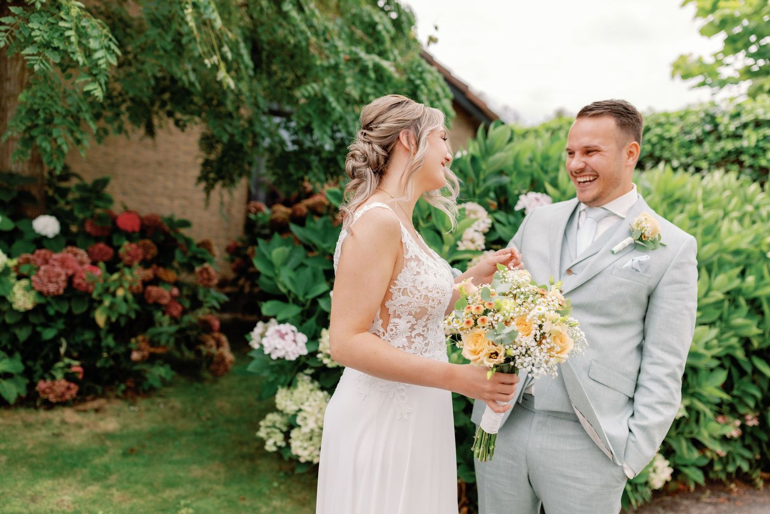 A couple shares a joyful moment together in a lush garden setting with blooming flowers and greenery.