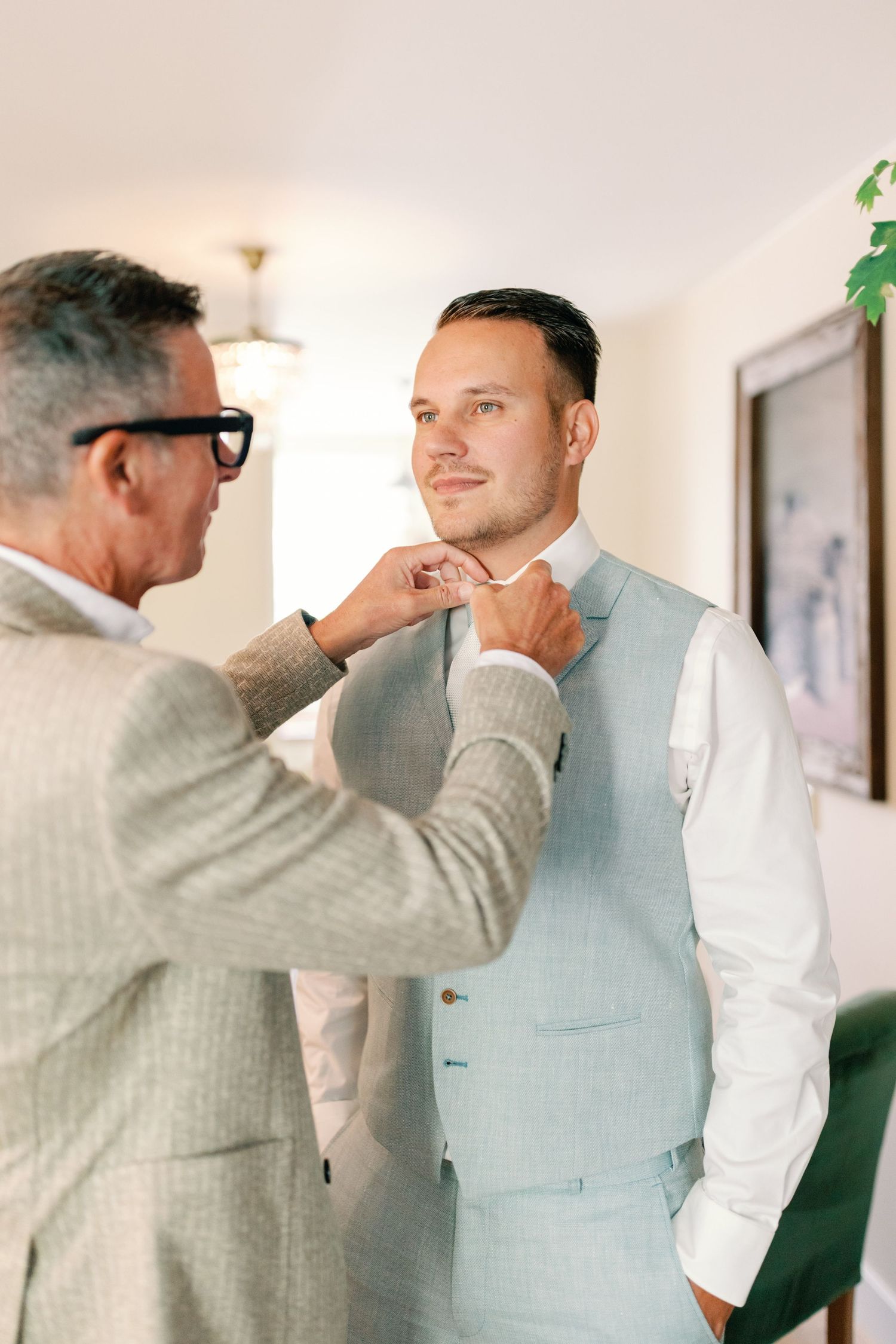 A sequence of photos showing someone helping another person adjust a light blue suit vest in a bright indoor setting.