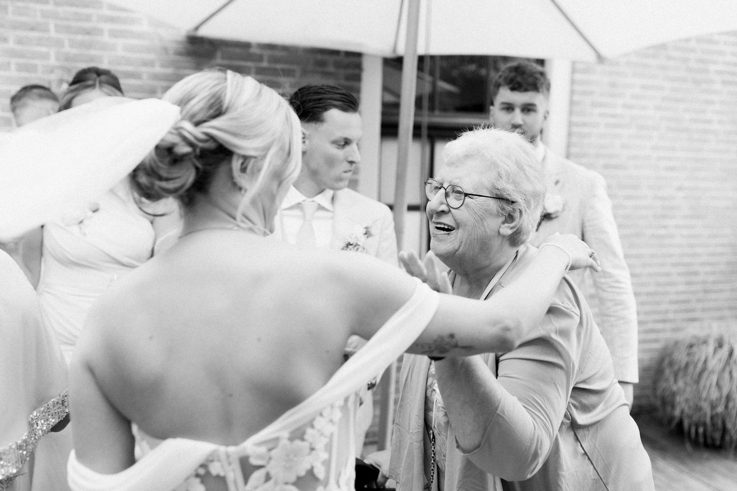 Black and white photo of wedding guests laughing and enjoying themselves at an outdoor reception.