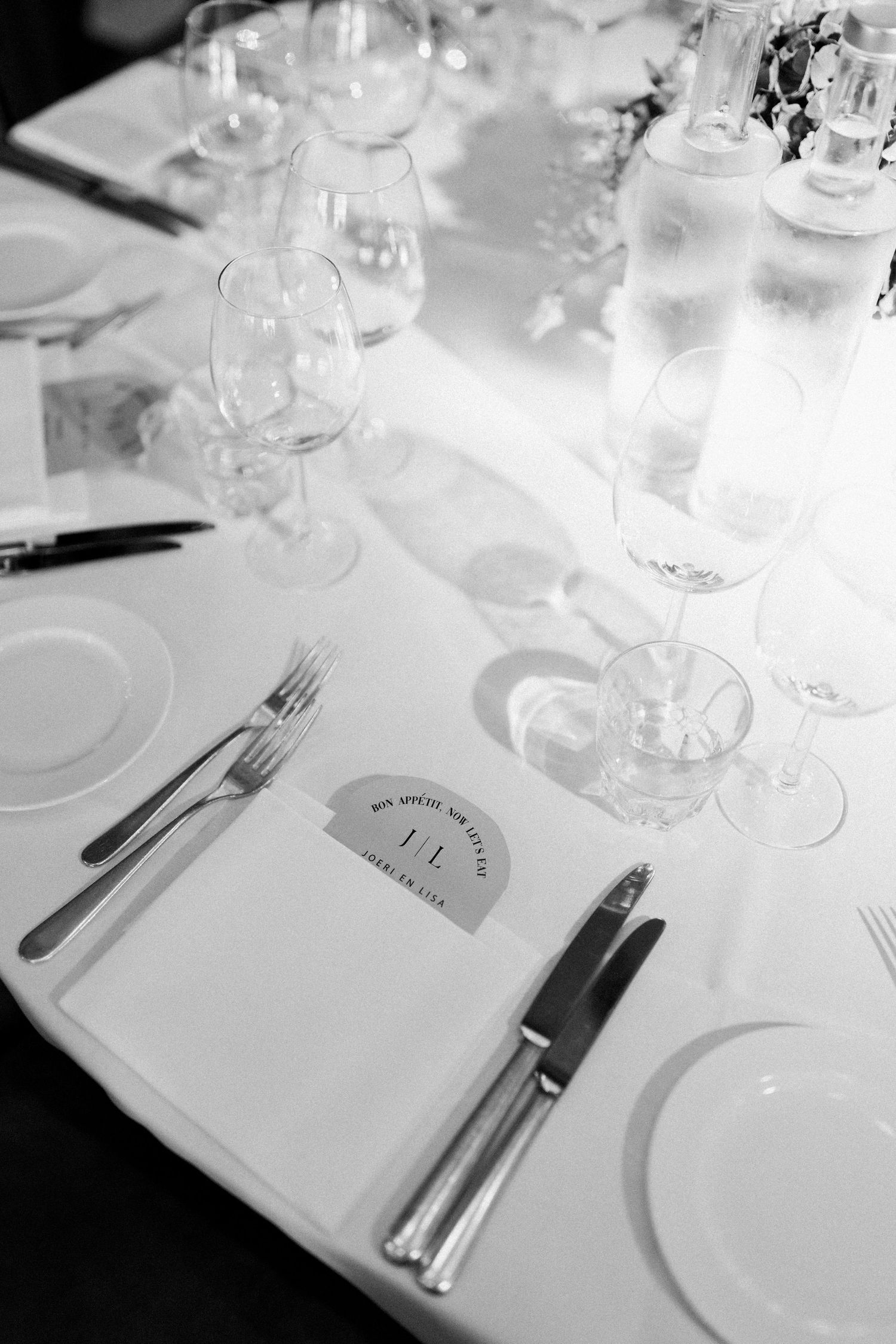 Elegant table settings with white plates, wine glasses and silverware arranged on crisp white tablecloths in a restaurant.