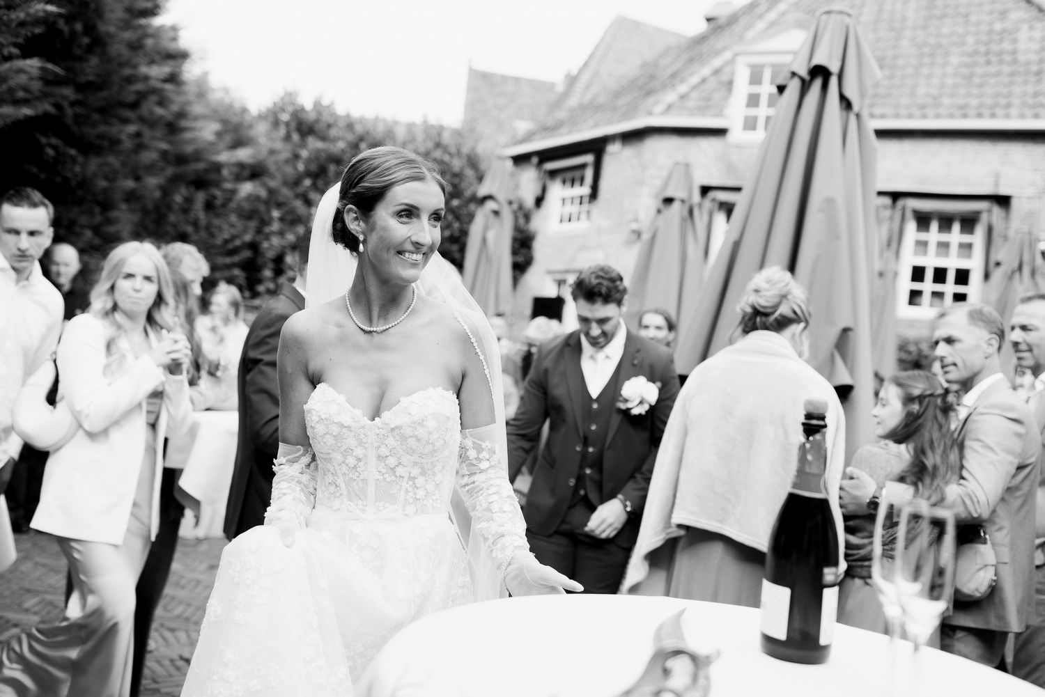 A black and white photo strip showing multiple wedding celebration moments with guests and newlyweds at a reception.