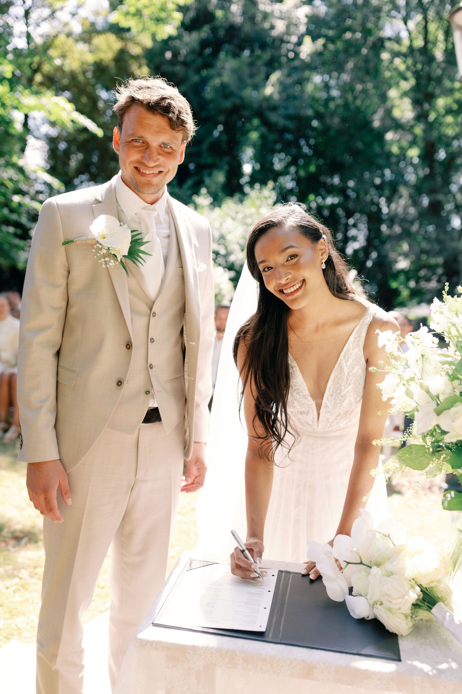 Couple in light-colored wedding attire share intimate moments during an outdoor summer photoshoot.