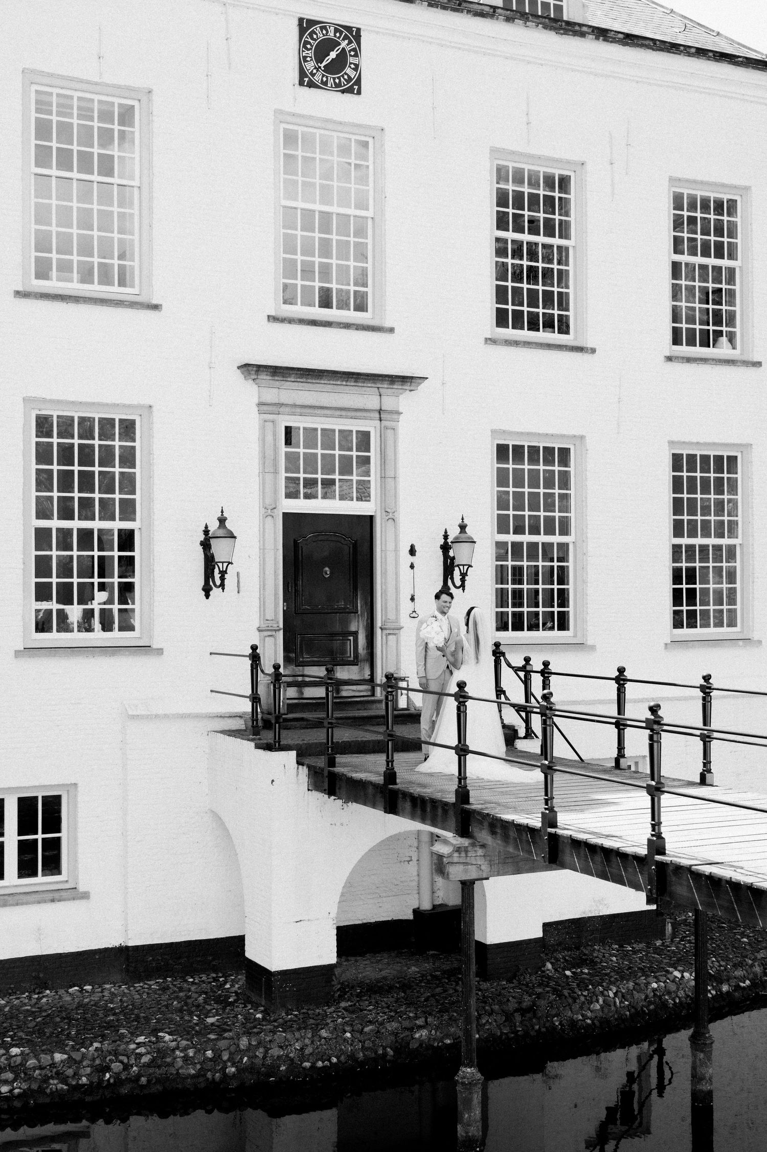 A white building facade with rows of Georgian windows and a black metal railing leading to entrance doors.