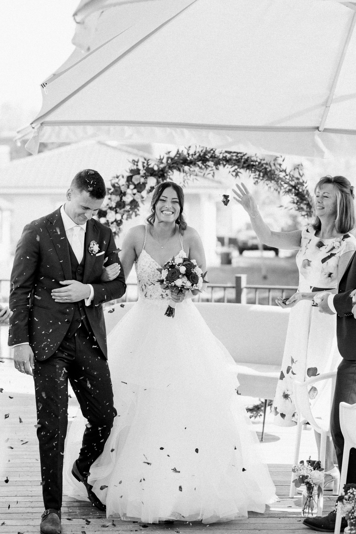 Confetti fills the air as couple celebrates under white tent at wedding reception.