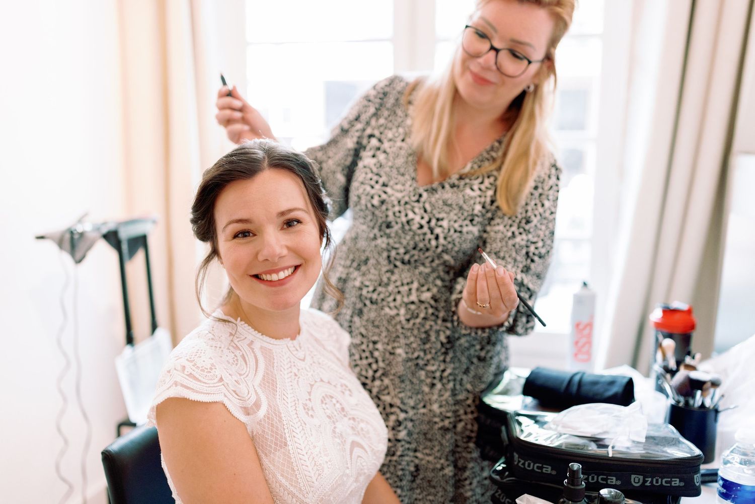 Bride getting ready for wedding day with hair and makeup being styled by professional stylists.