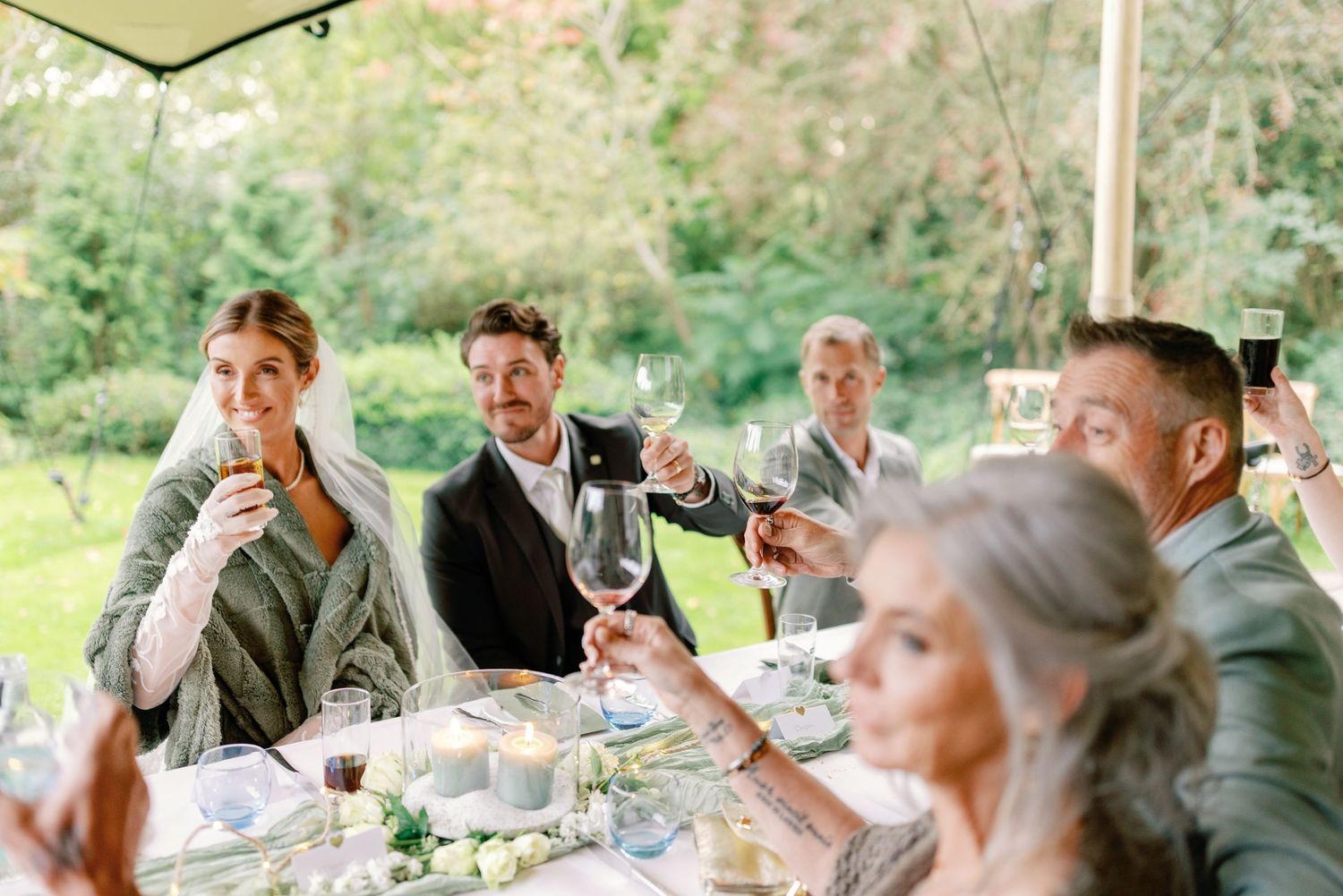 Guests enjoying conversation and wine at an outdoor dinner party with rustic table settings in a garden setting.
