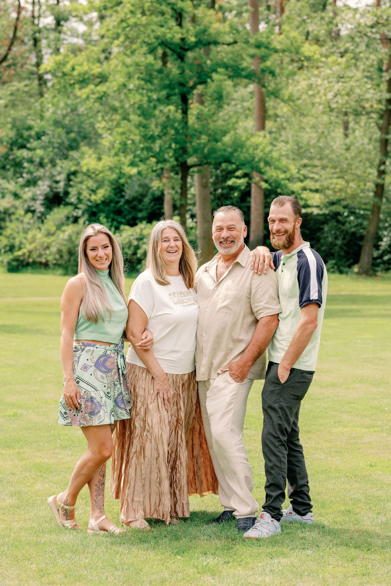 Casual outdoor family portrait with group members wearing coordinated white and neutral outfits.