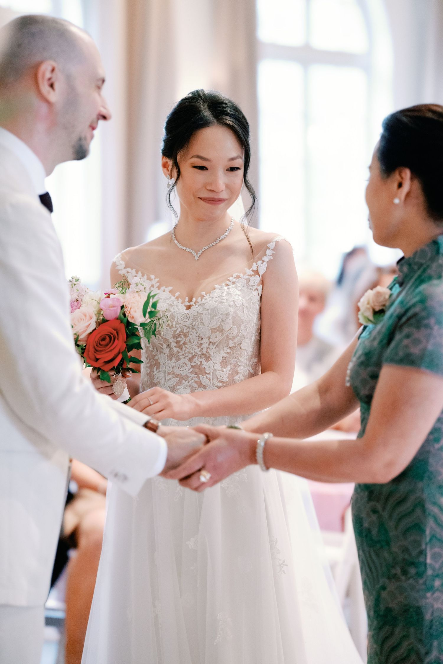 Wedding ceremony moment showing couple holding hands with officiant during intimate indoor celebration.