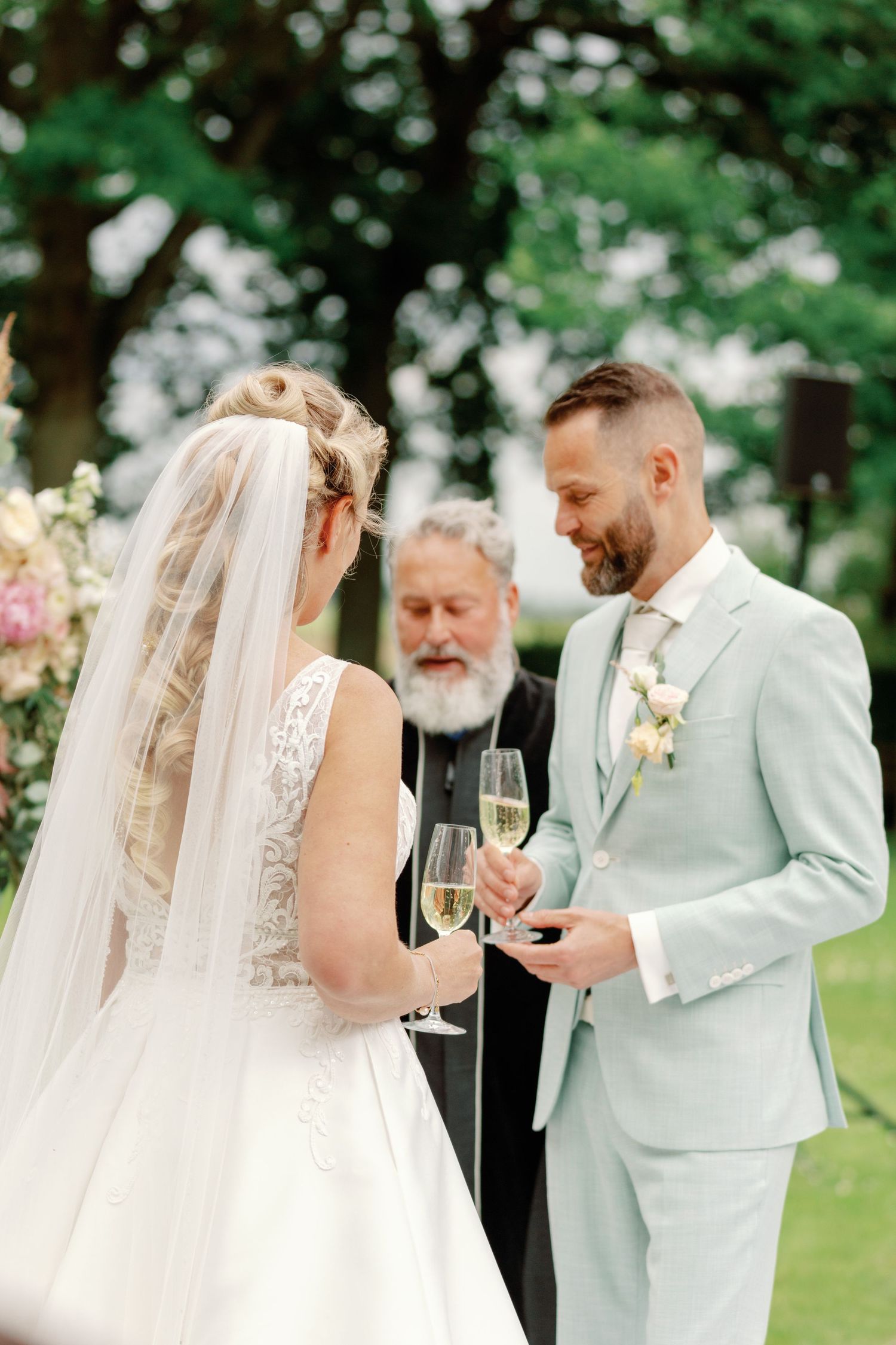 A couple shares joyful moments during their outdoor wedding ceremony in a lush garden setting.