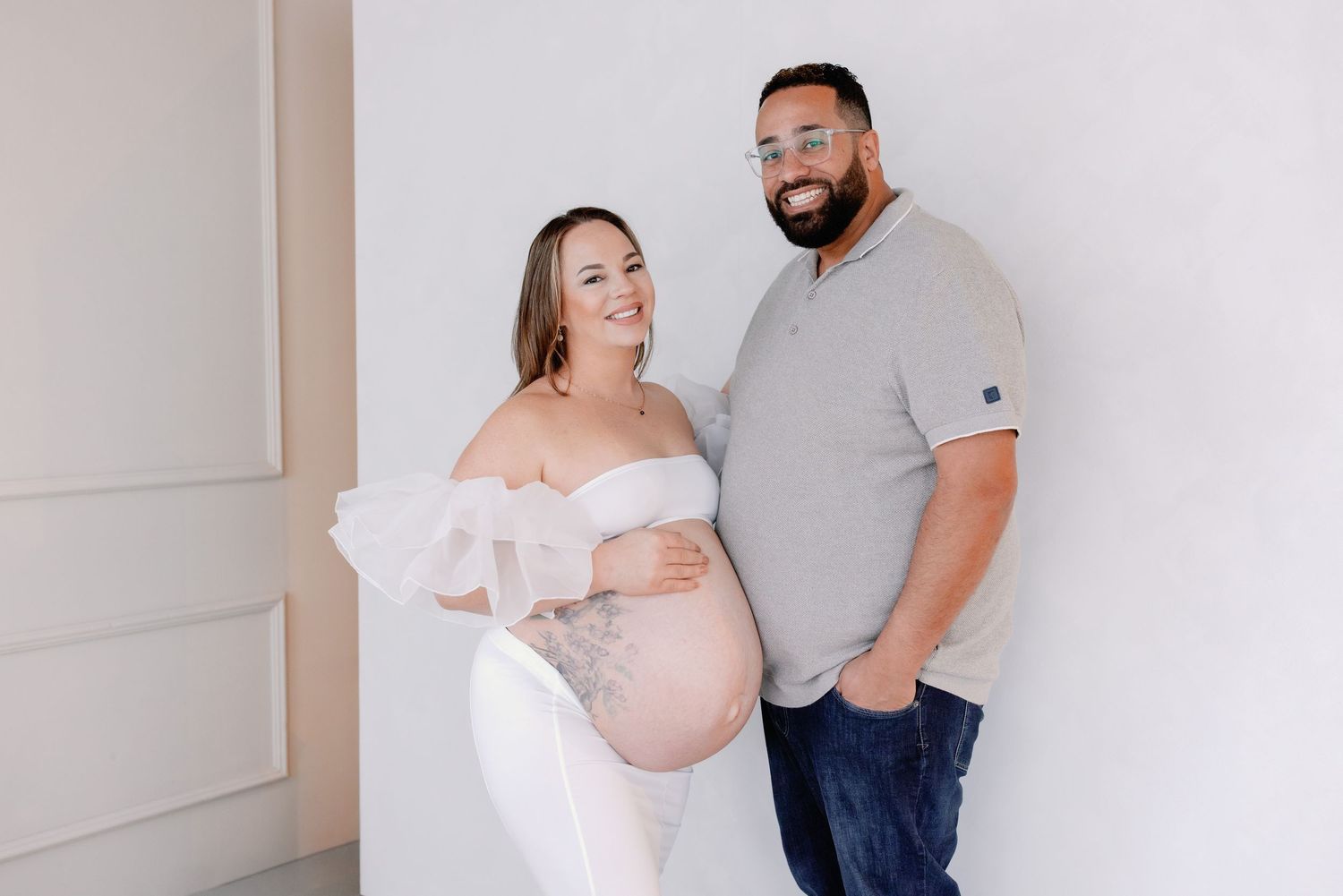 A series of maternity photos showing a couple in soft neutral tones against a white wall.